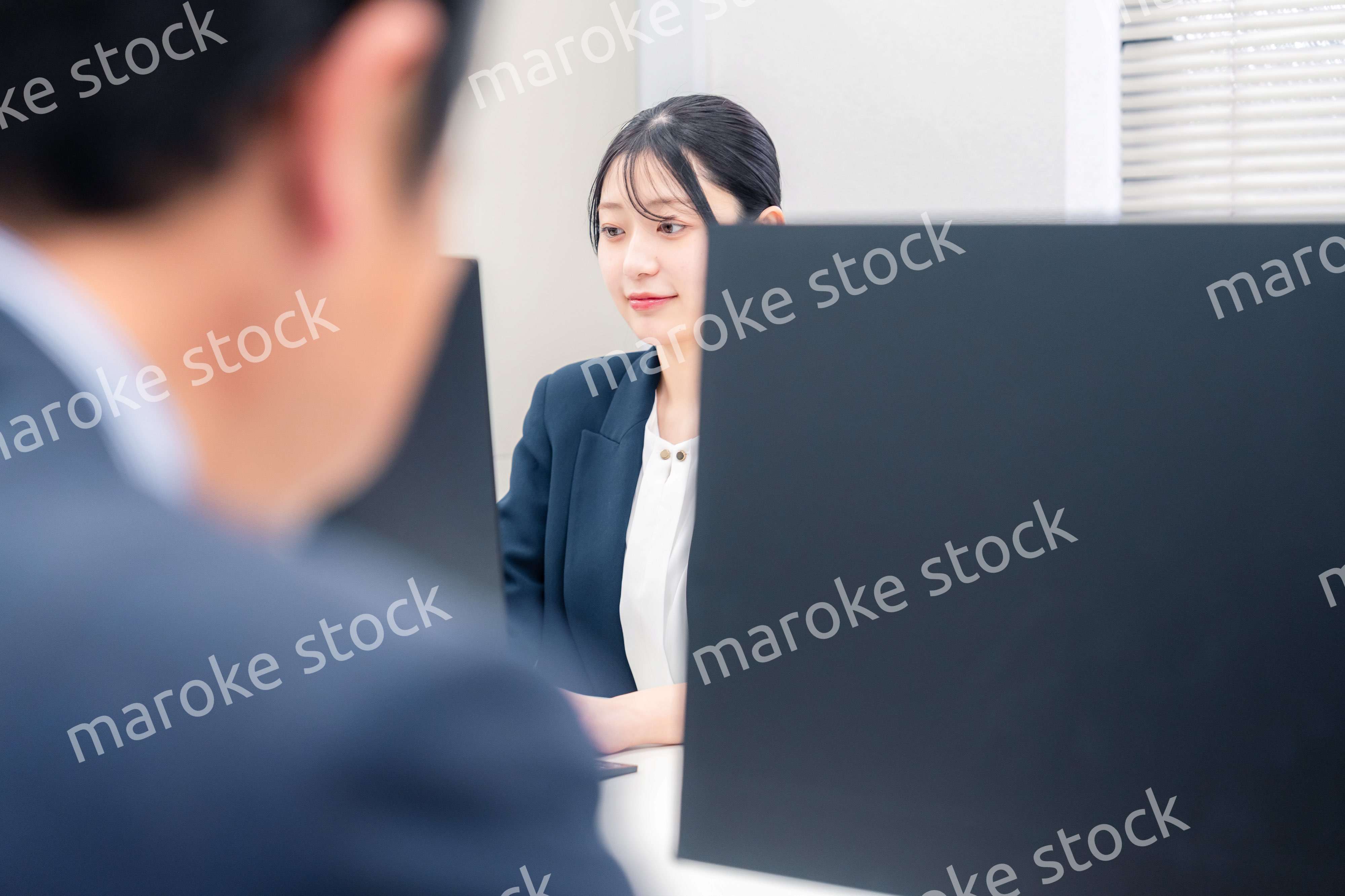 オフィスで生き生きとデスクワークをする若い女性