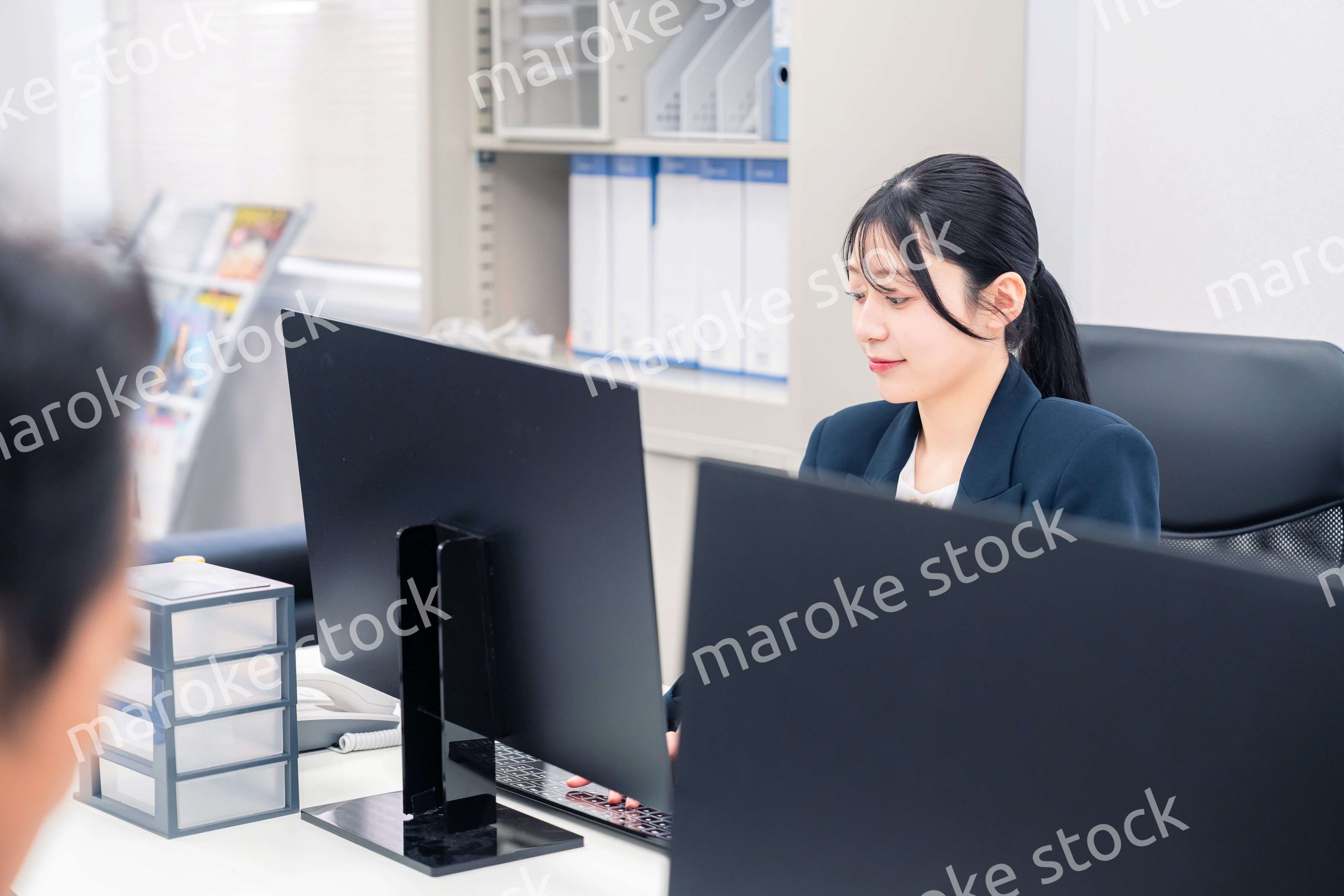 オフィスで生き生きとデスクワークをする若い女性