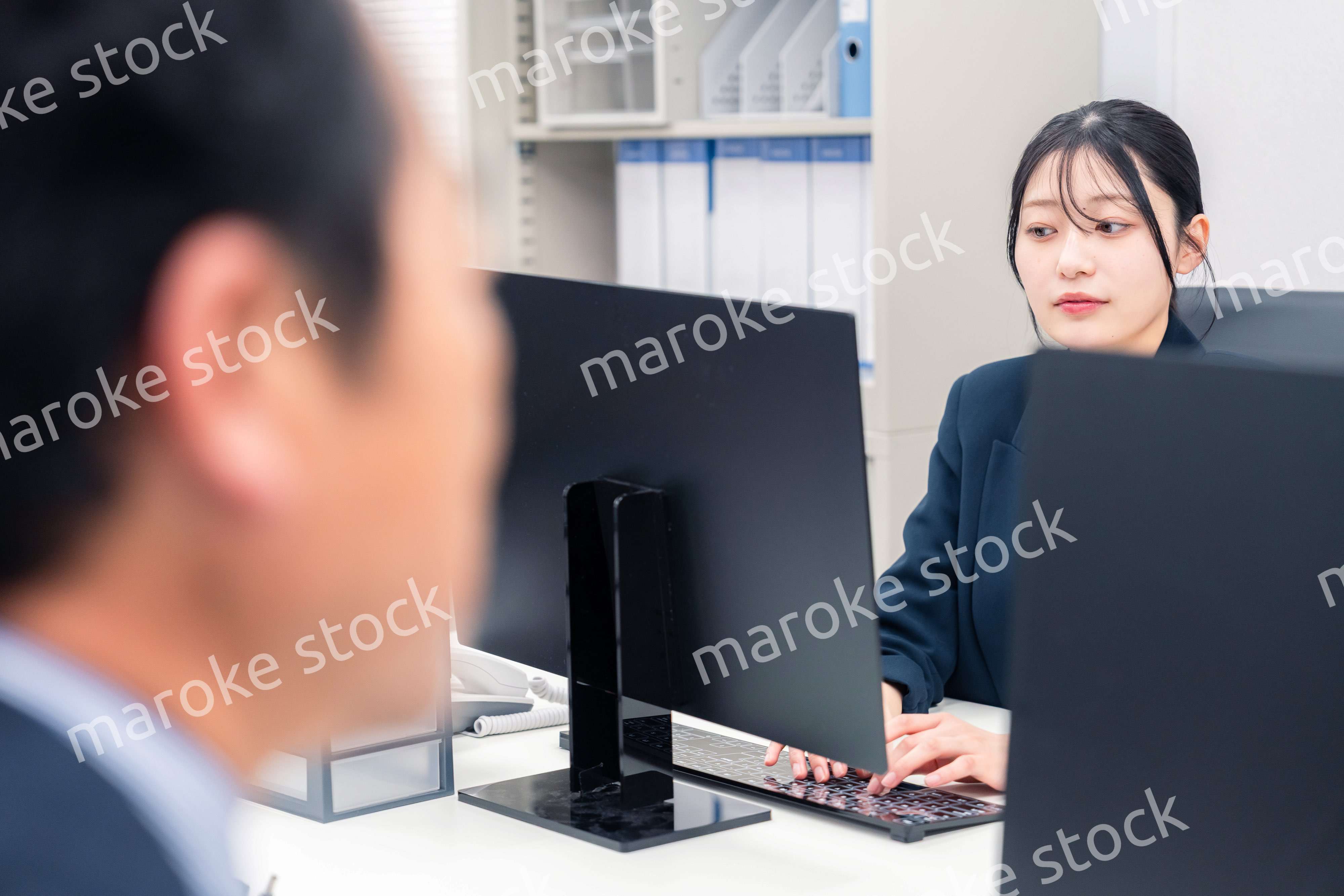 オフィスで生き生きとデスクワークをする若い女性