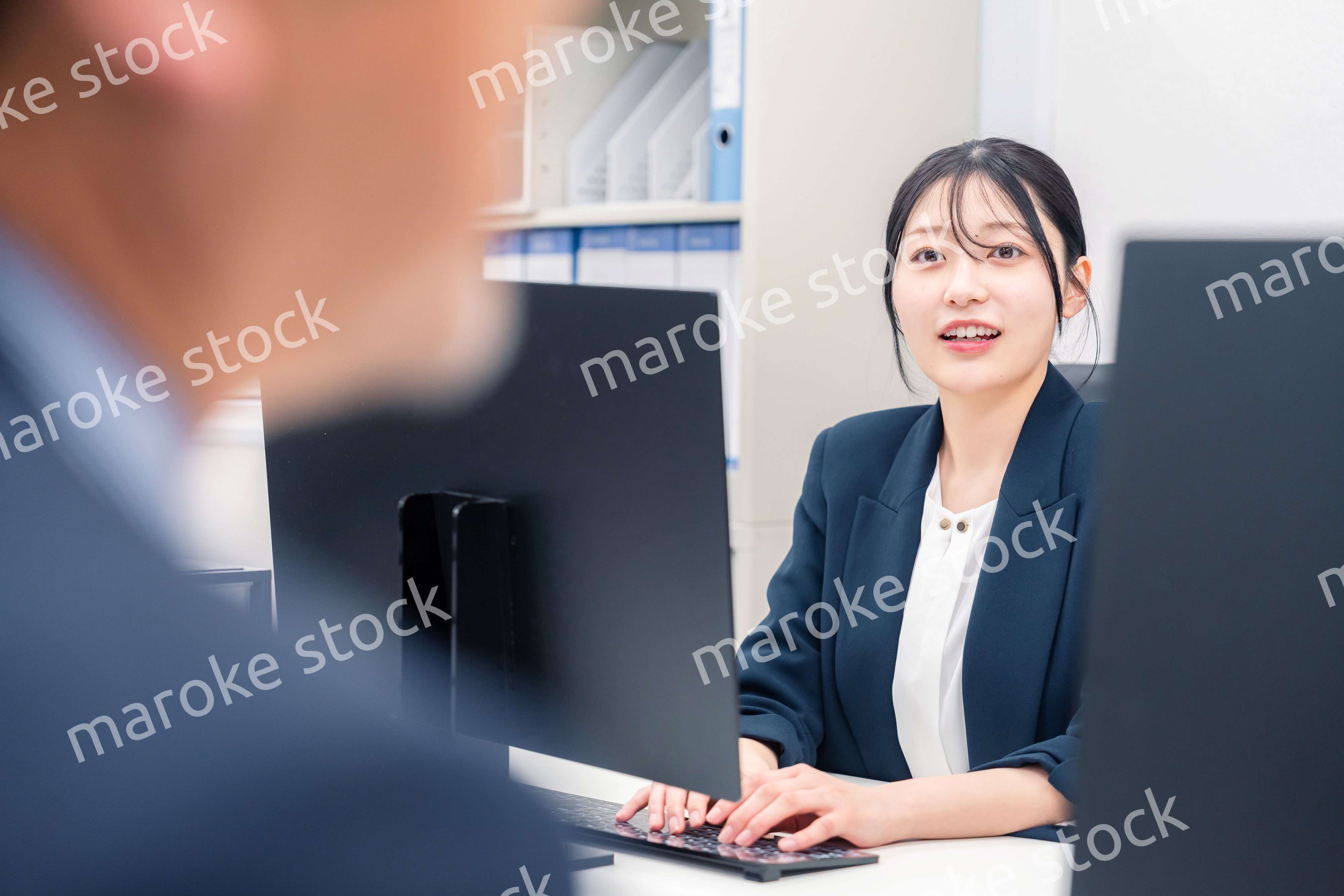 オフィスで生き生きとデスクワークをする若い女性