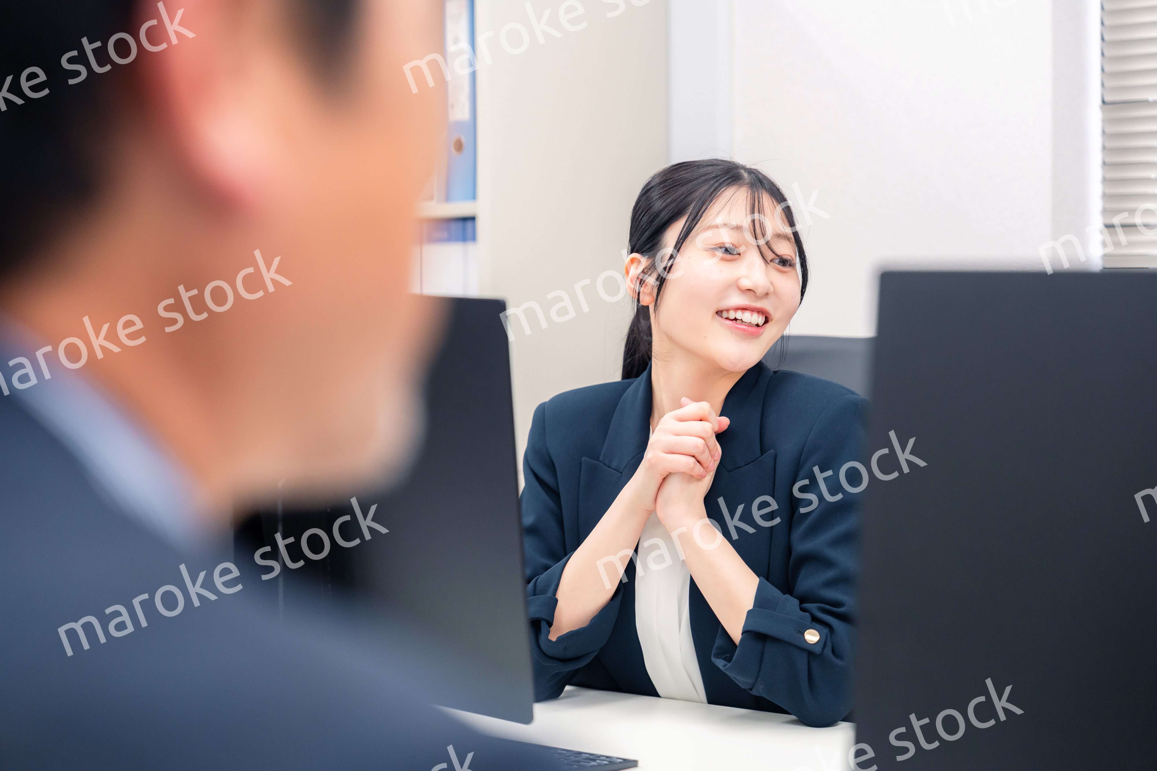 オフィスで生き生きとデスクワークをする若い女性