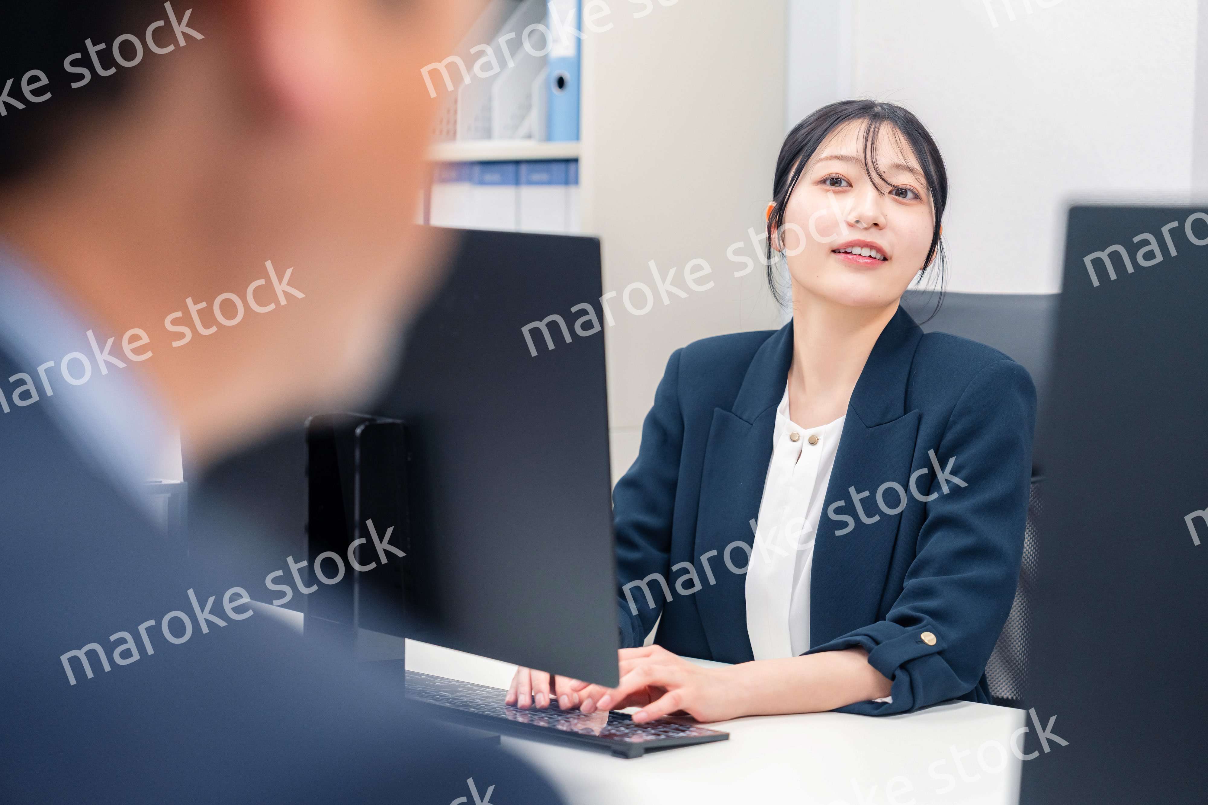 オフィスで生き生きとデスクワークをする若い女性