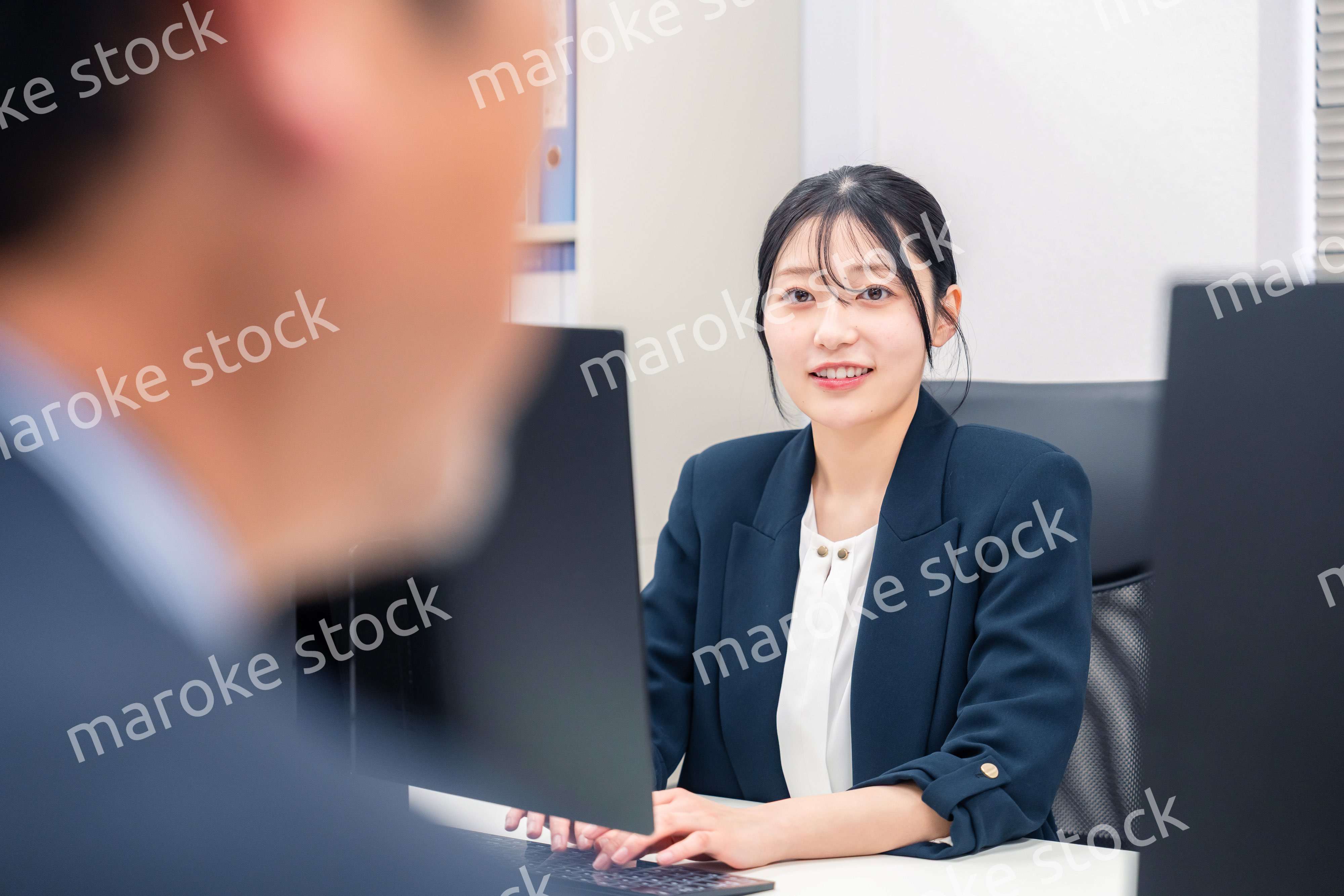 オフィスで生き生きとデスクワークをする若い女性