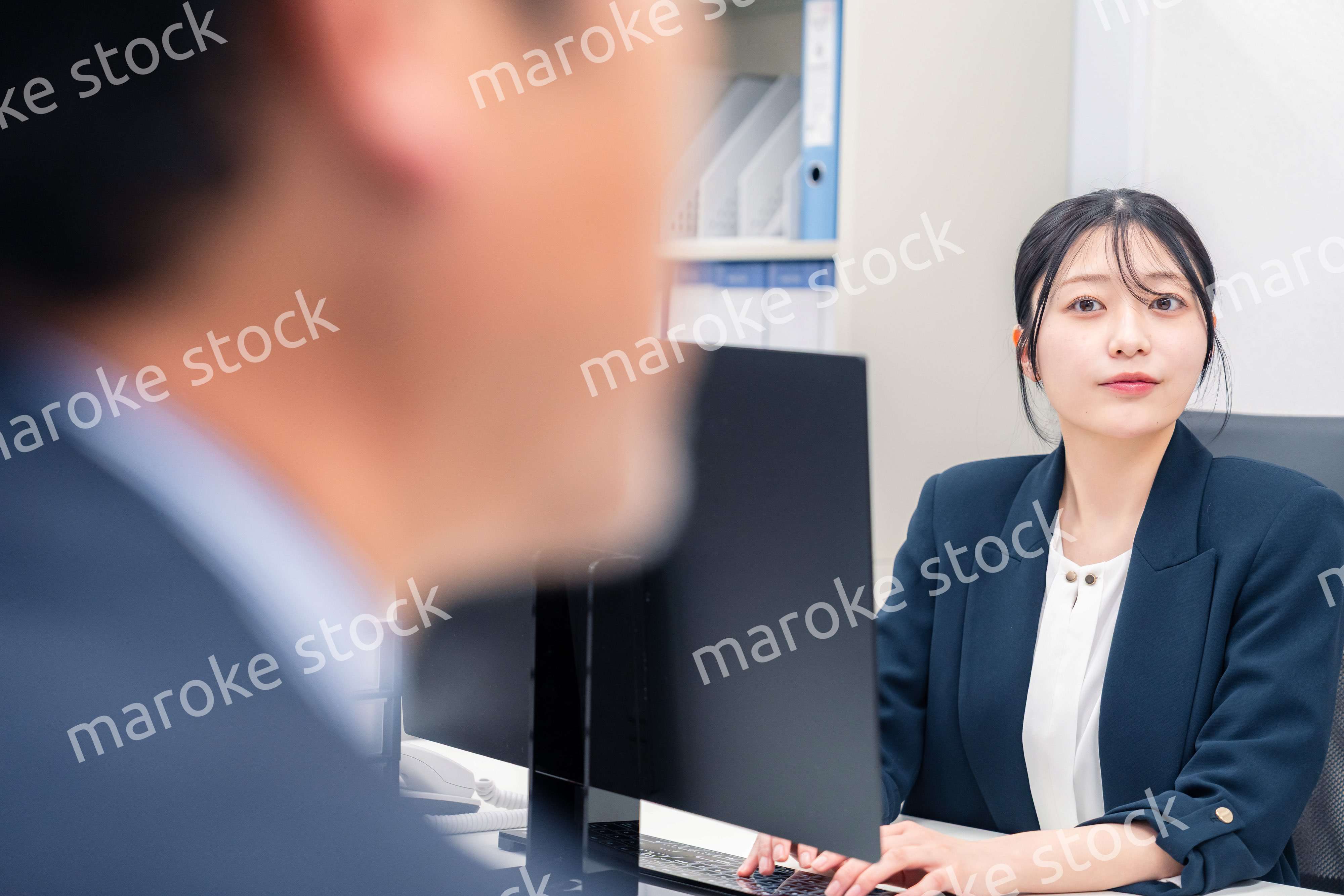 オフィスで生き生きとデスクワークをする若い女性