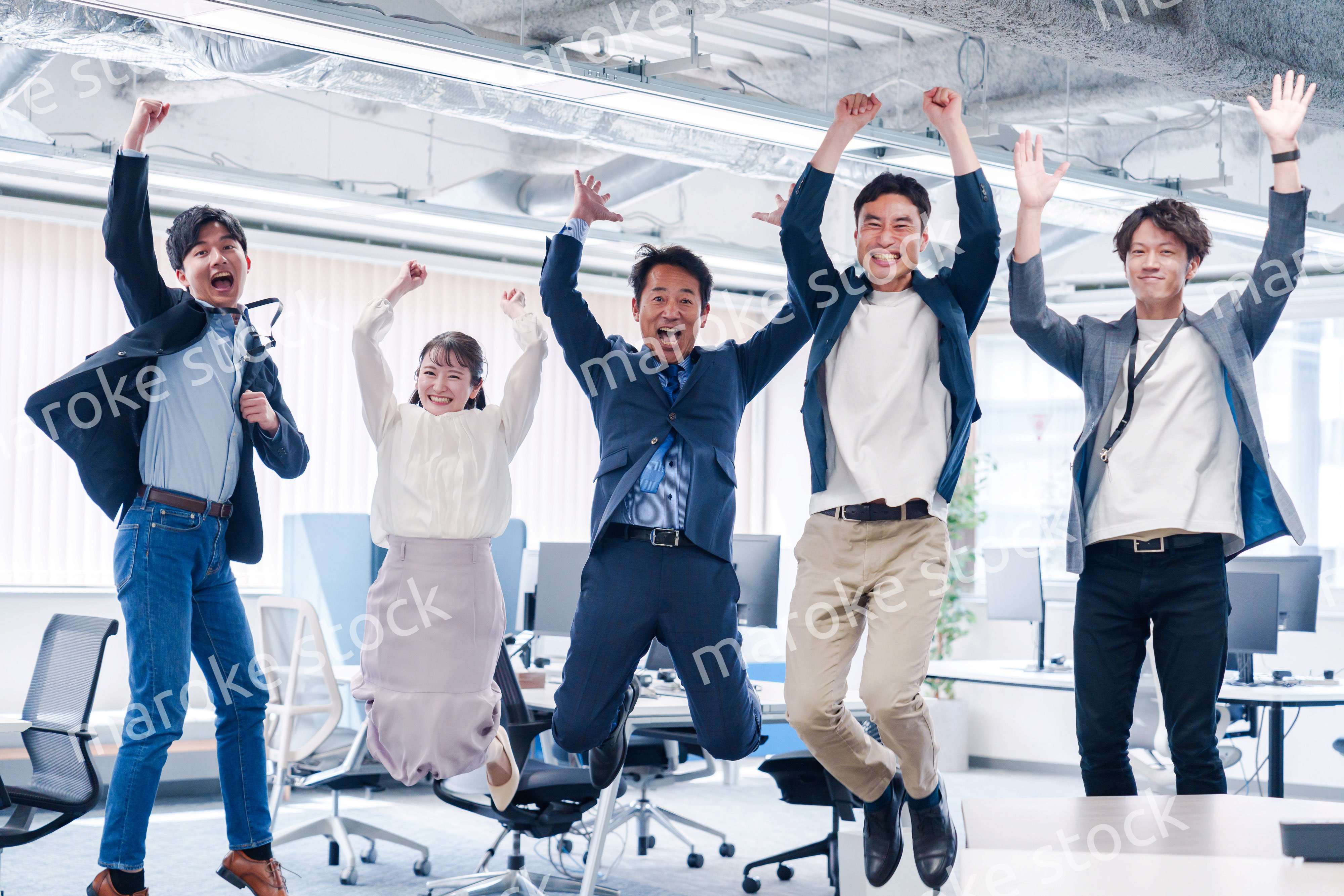 オフィスで大喜びをしてジャンプをするビジネスパーソン