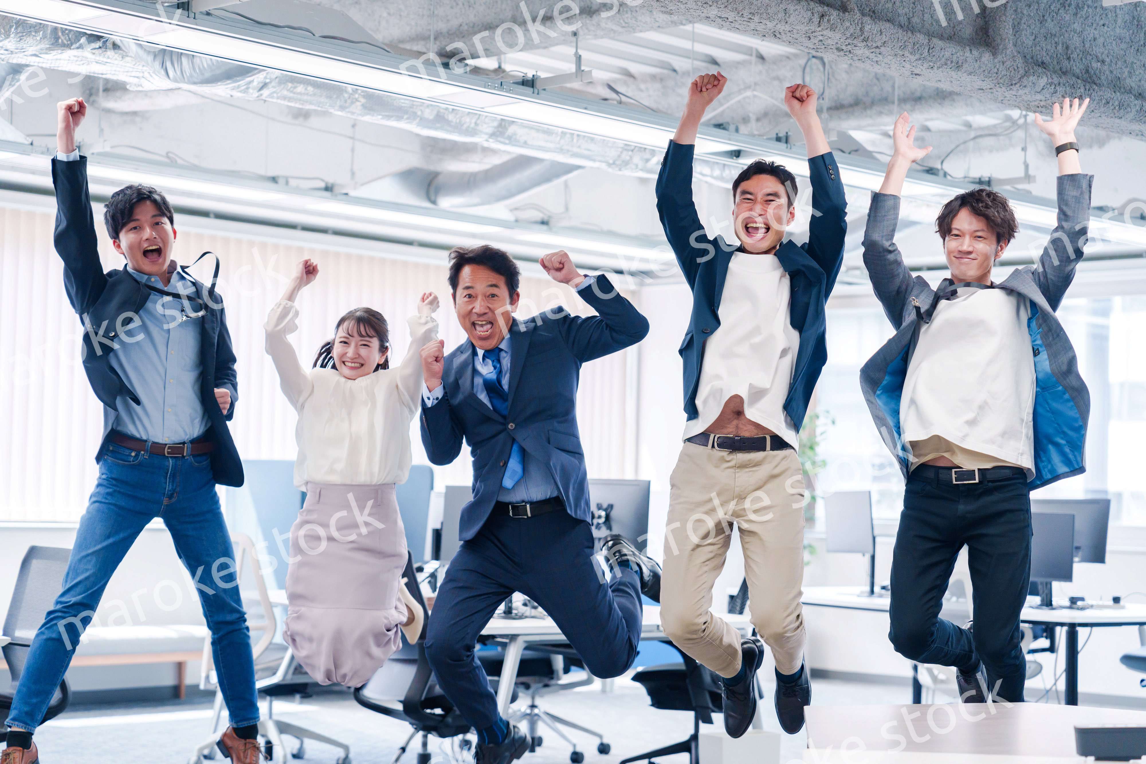 オフィスで大喜びをしてジャンプをするビジネスパーソン