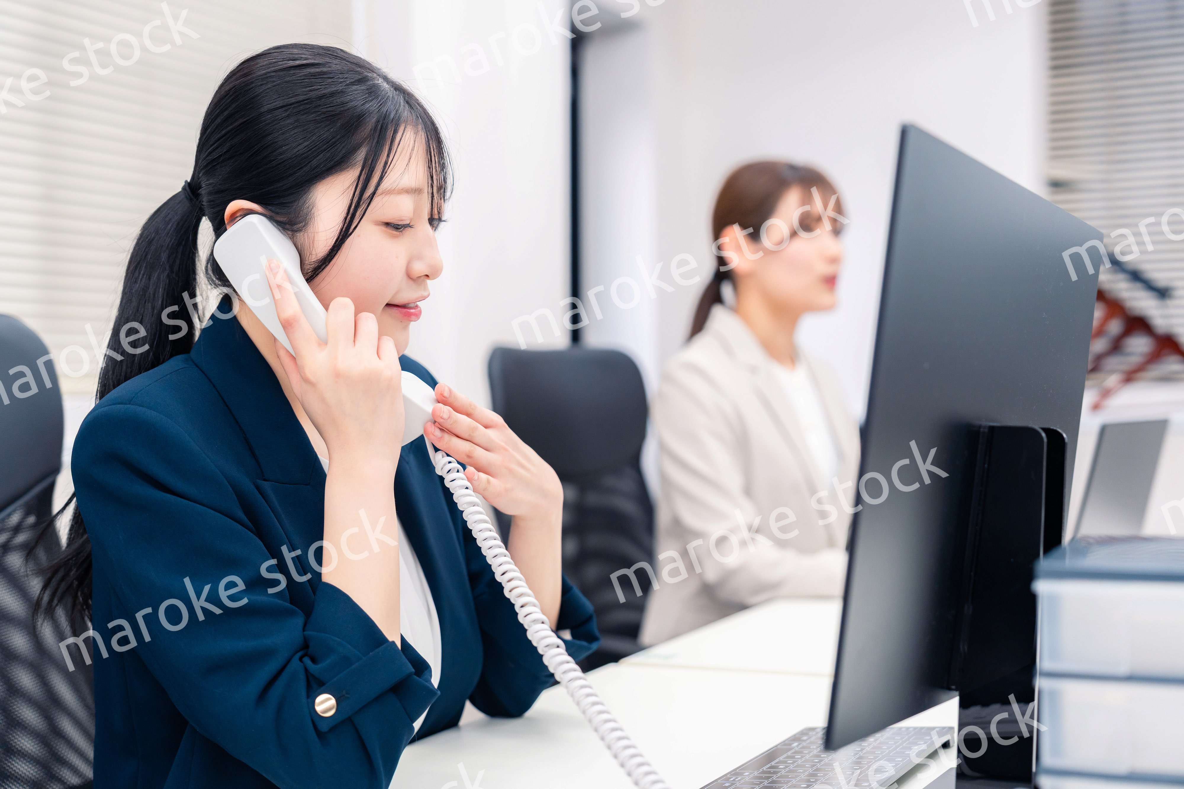 オフィスでにこやかに電話対応をするビジネスウーマン