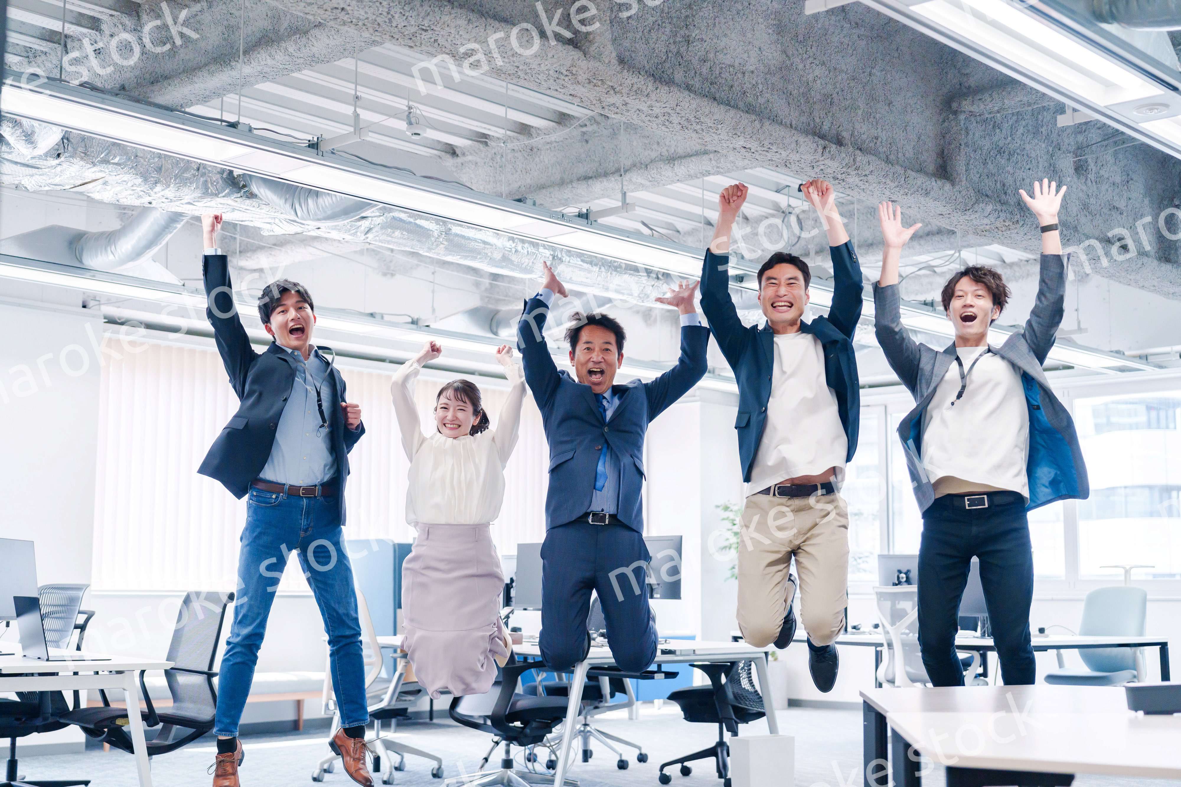 オフィスで大喜びをしてジャンプをするビジネスパーソン