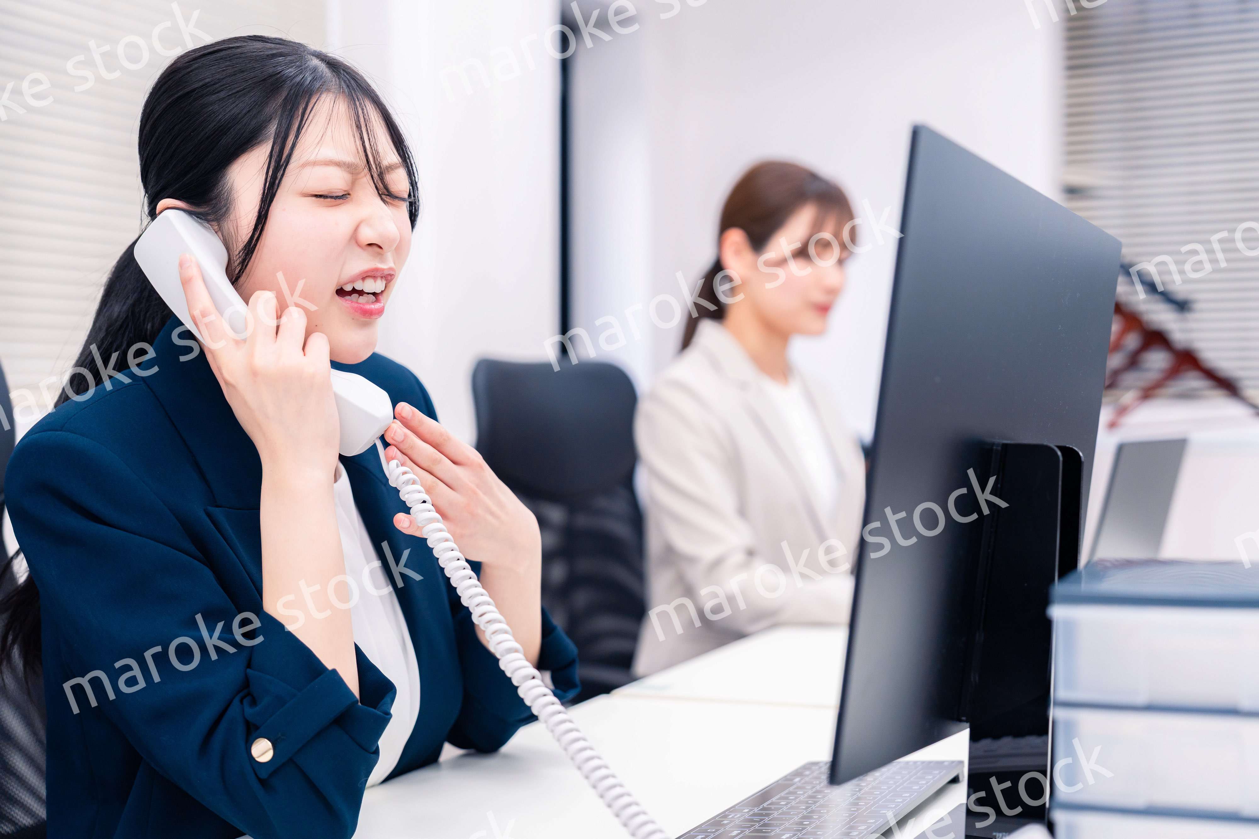 オフィスでお詫びの電話をする若いキャリアウーマン
