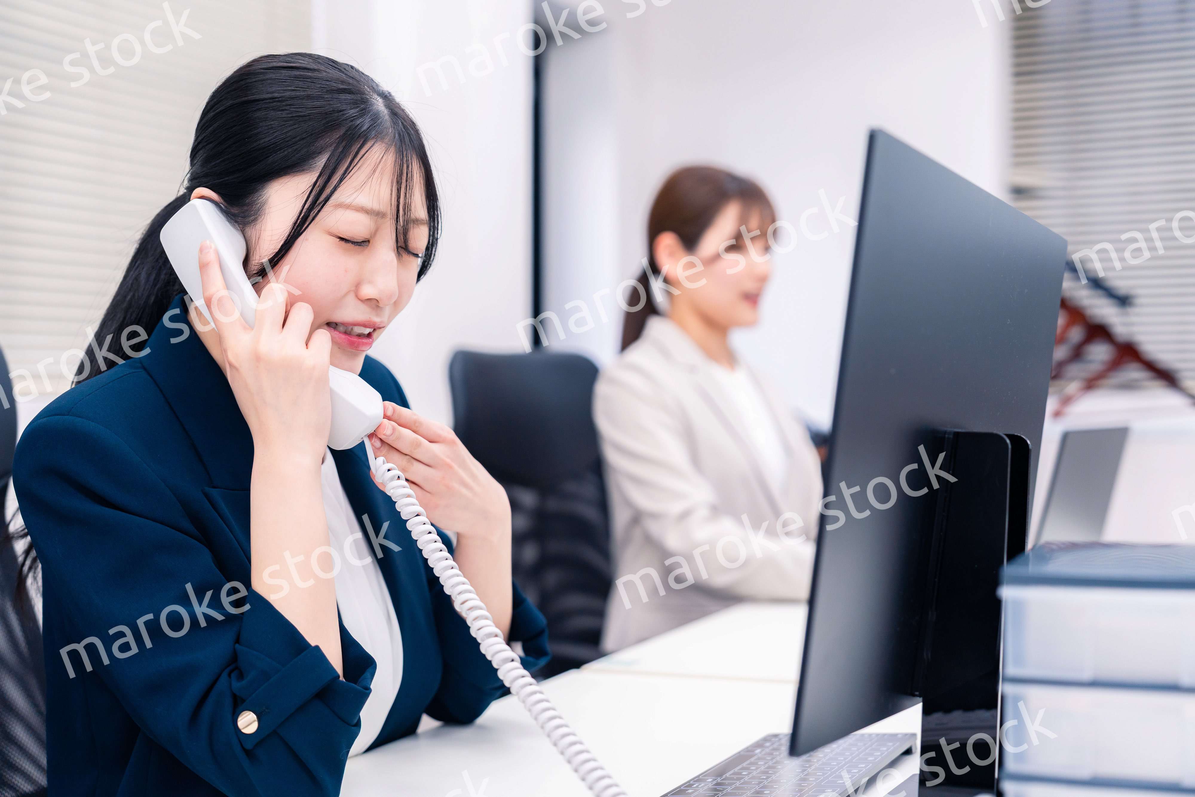 オフィスでお詫びの電話をする若いキャリアウーマン