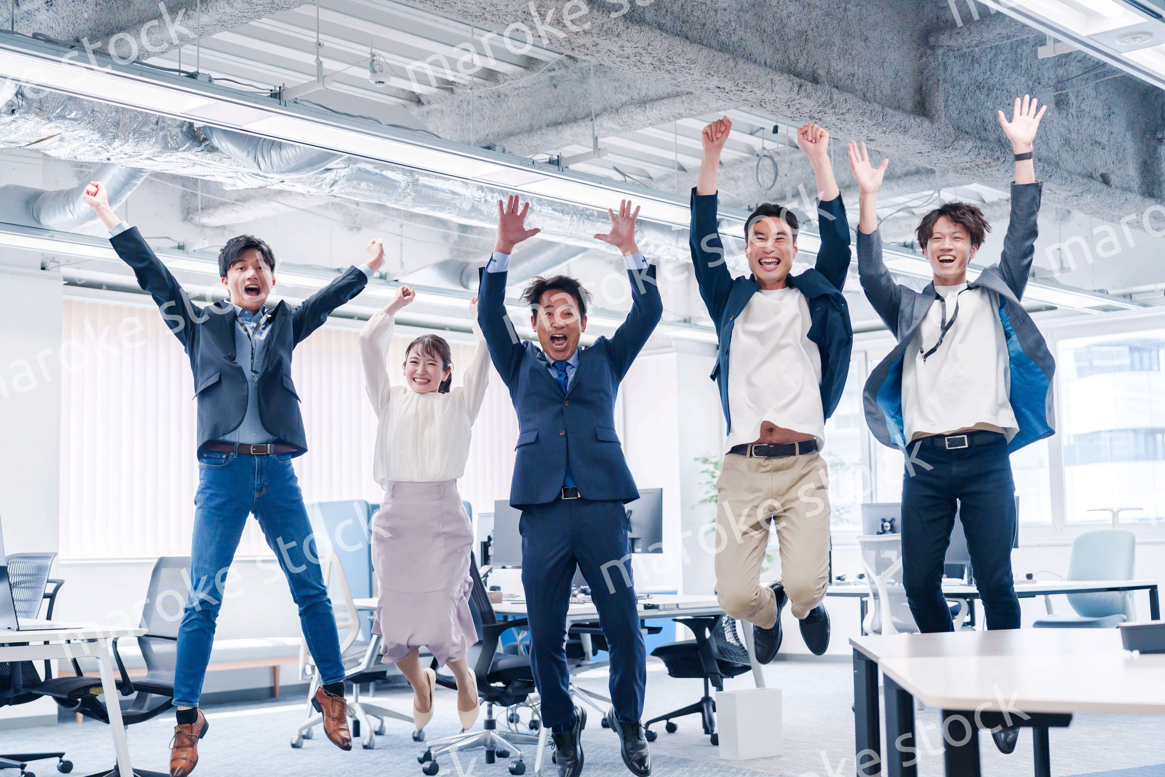 オフィスで大喜びをしてジャンプをするビジネスパーソン