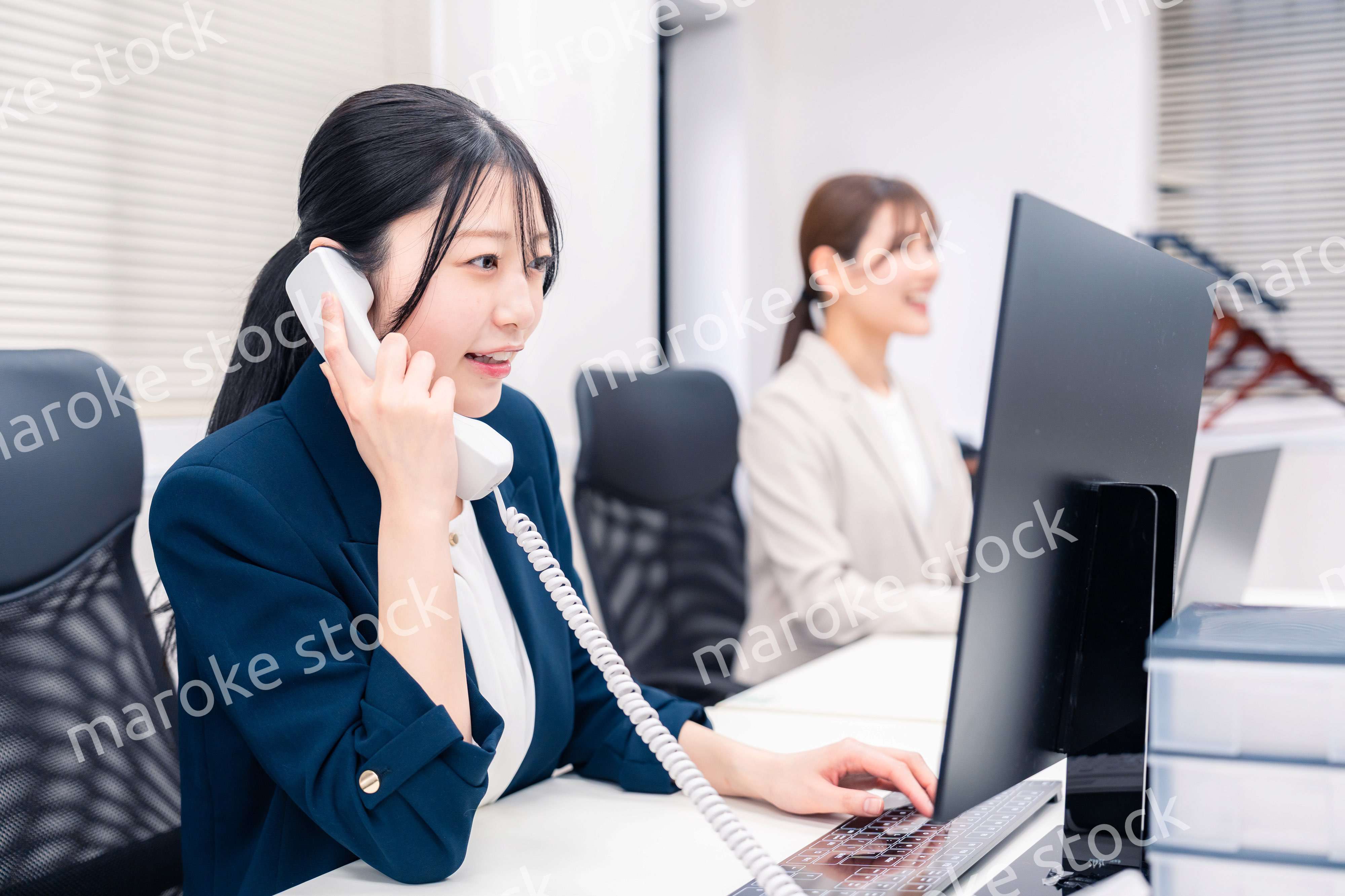 オフィスでにこやかに電話対応をするビジネスウーマン