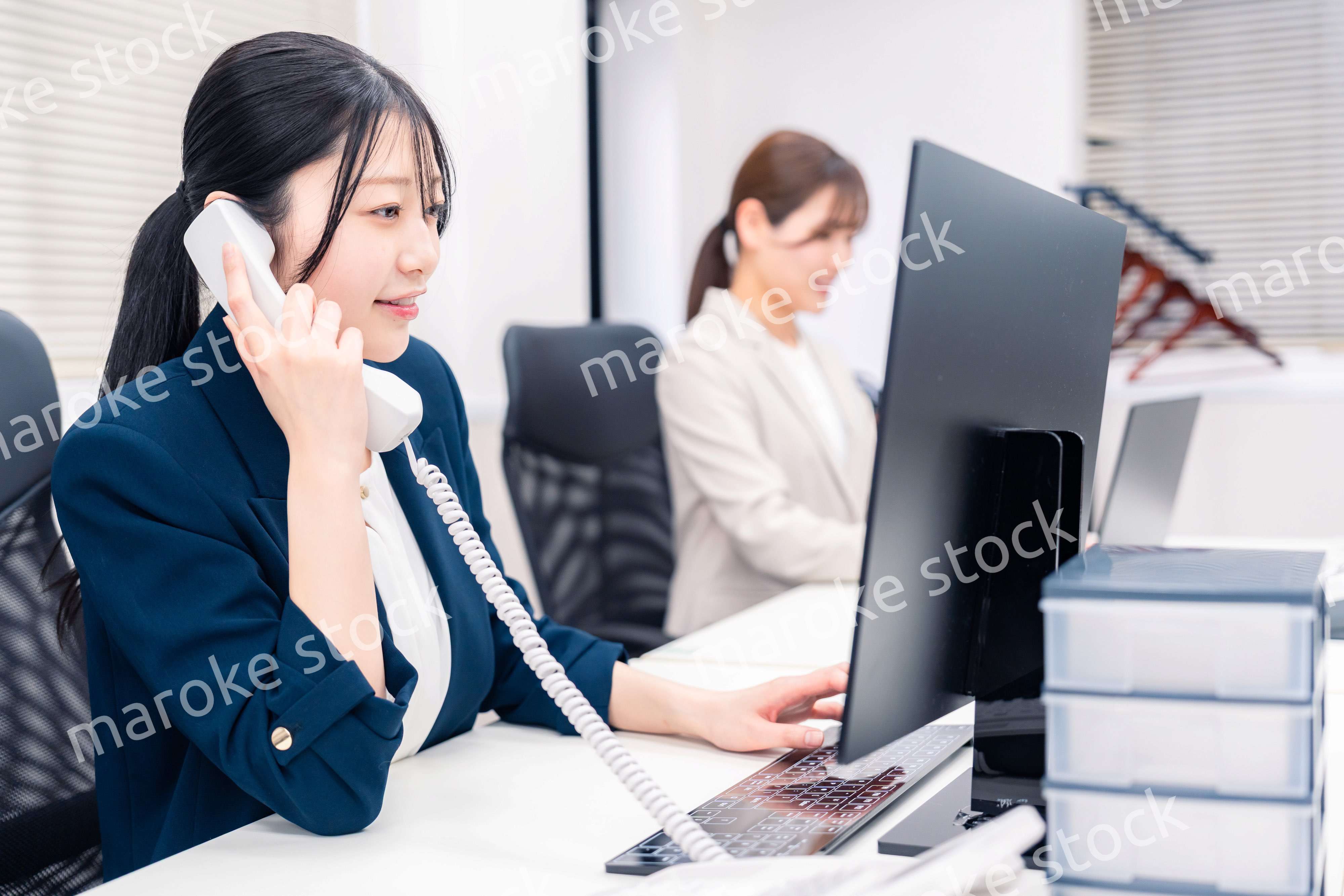 オフィスでにこやかに電話対応をするビジネスウーマン