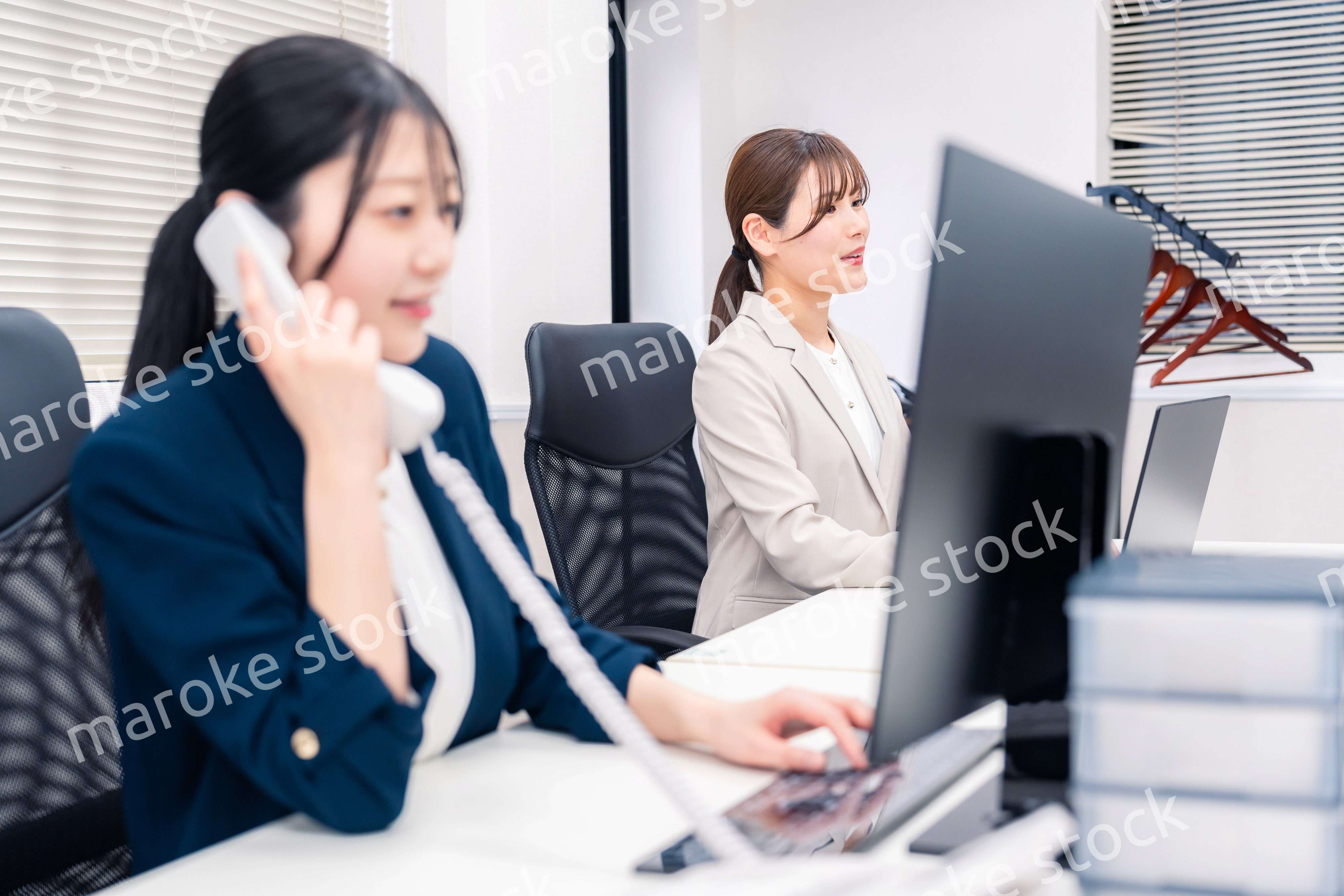 オフィスでにこやかに電話対応をするビジネスウーマン