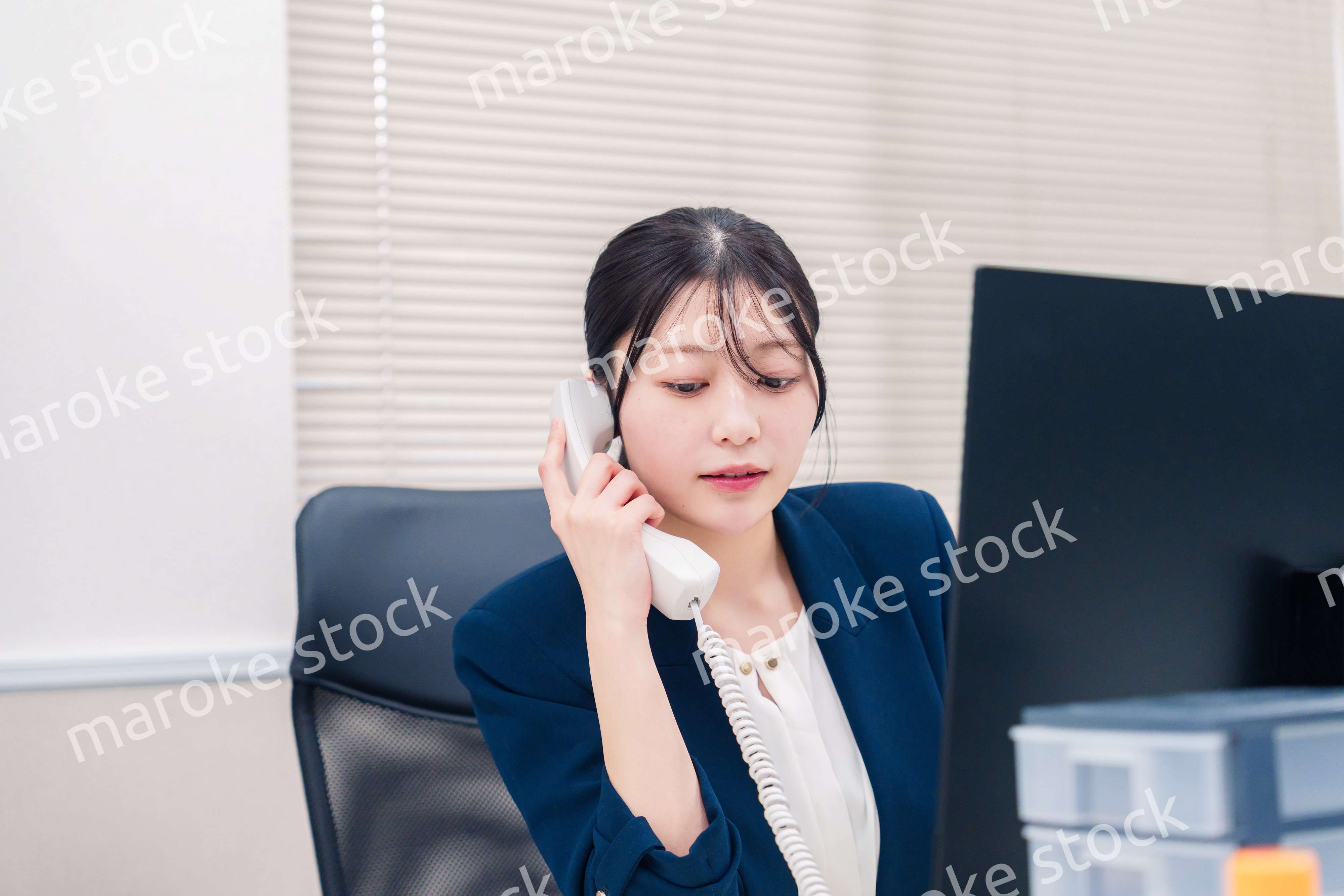 オフィスの固定電話で通話をする女性ビジネスパーソン