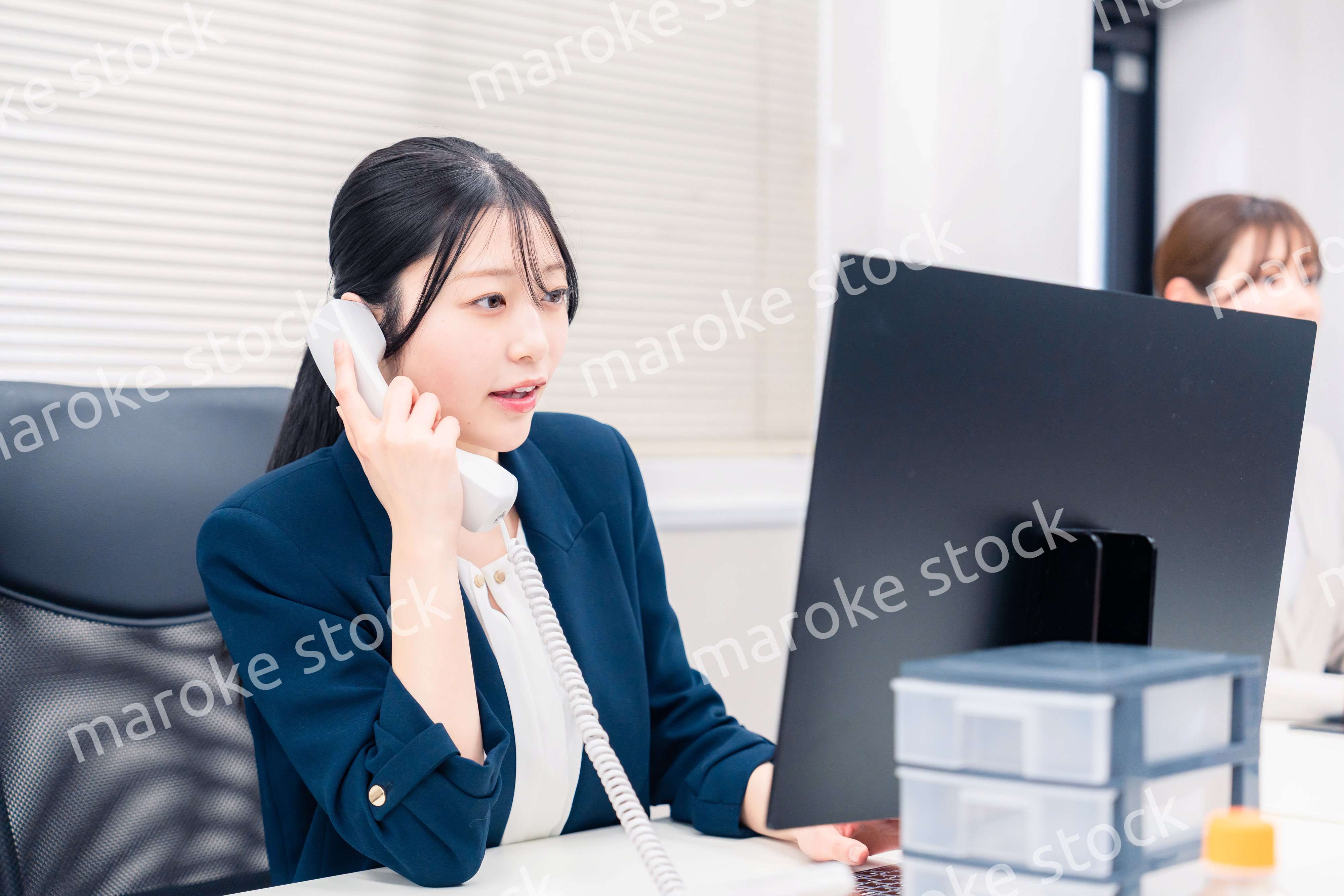 オフィスでにこやかに電話対応をするビジネスウーマン