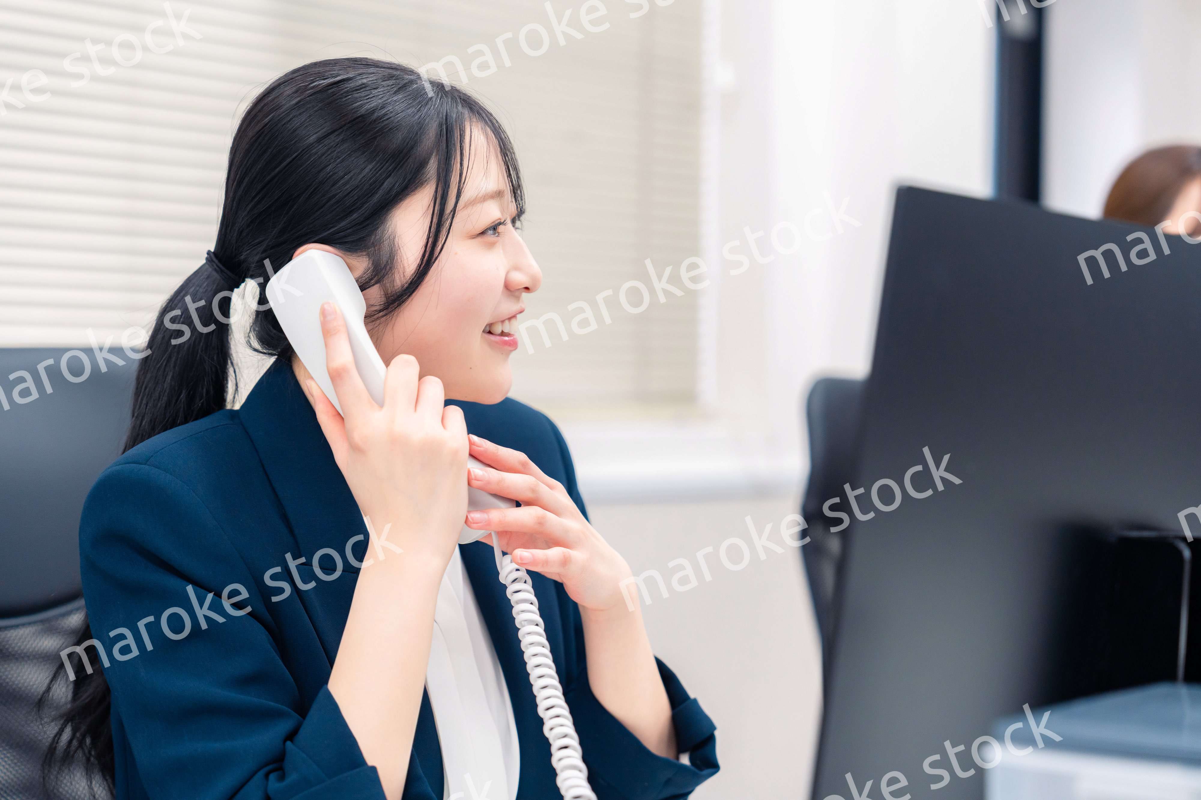 オフィスでにこやかに電話対応をするビジネスウーマン