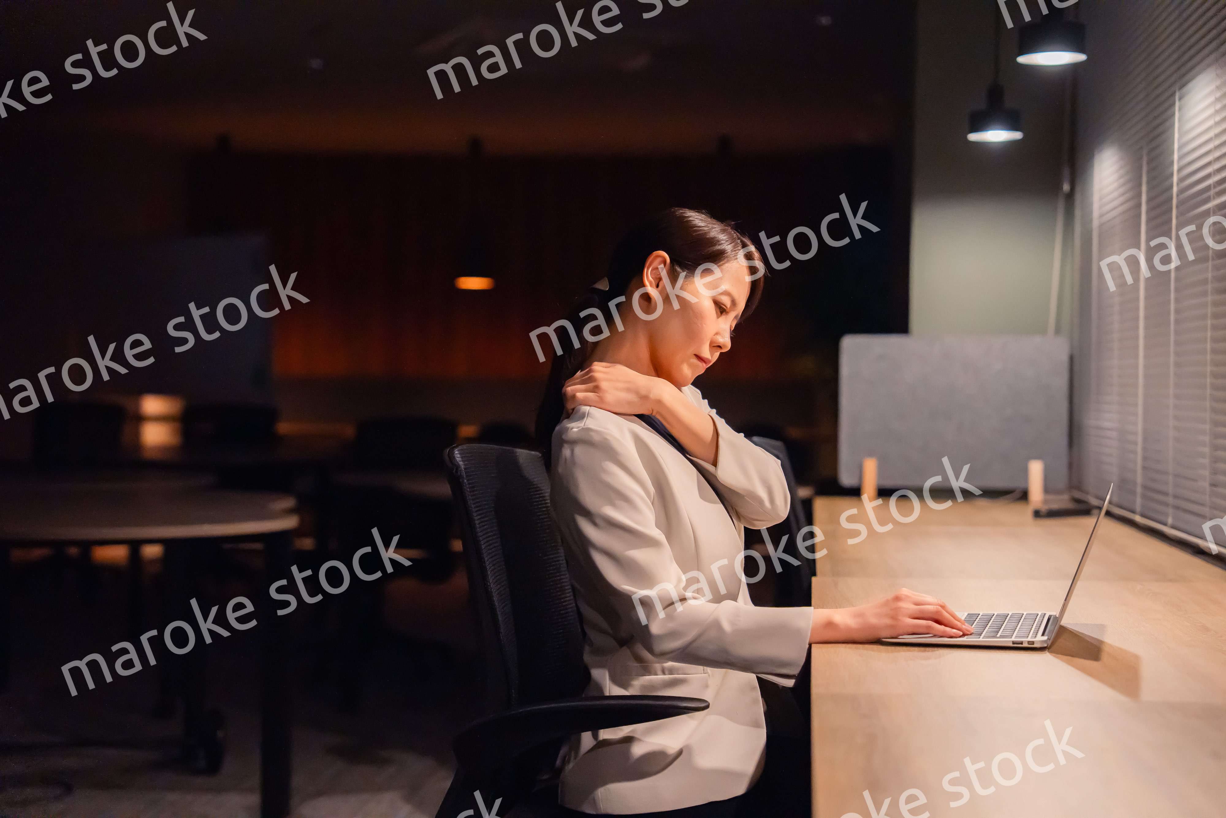 オフィスで暗くなるまで残業をして疲れる女性管理職