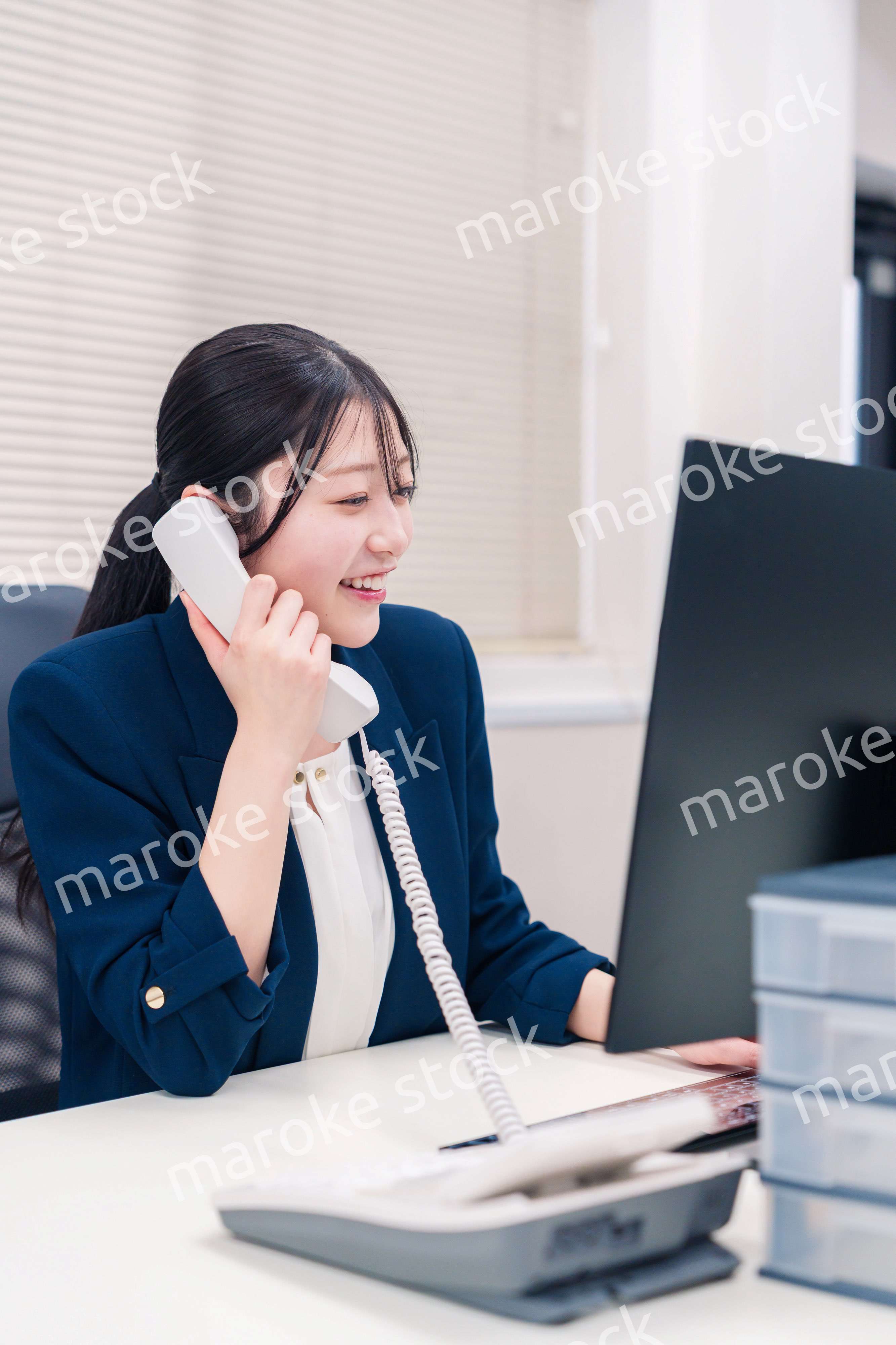 オフィスの固定電話で通話をする女性ビジネスパーソン