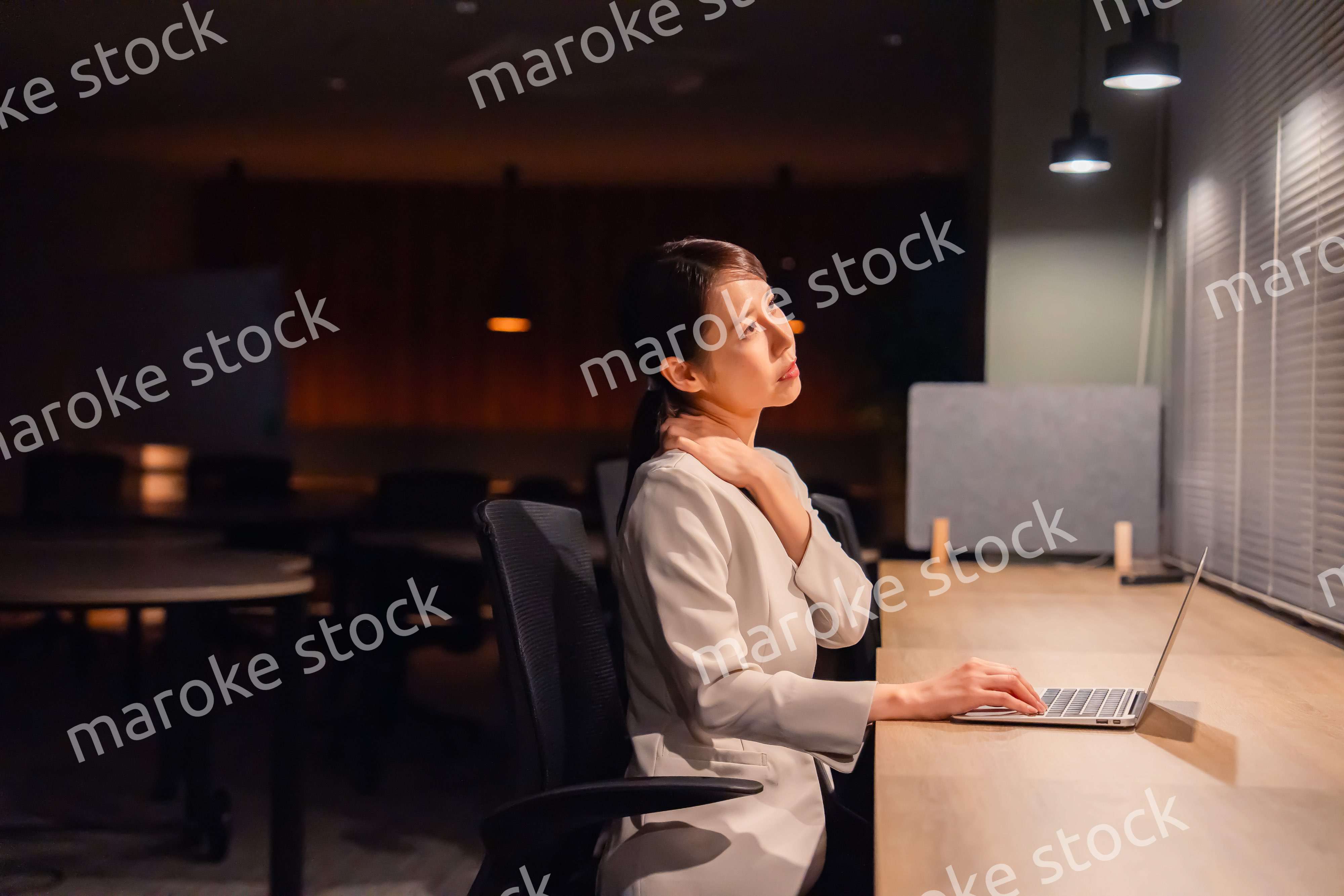 オフィスで暗くなるまで残業をして疲れる女性管理職