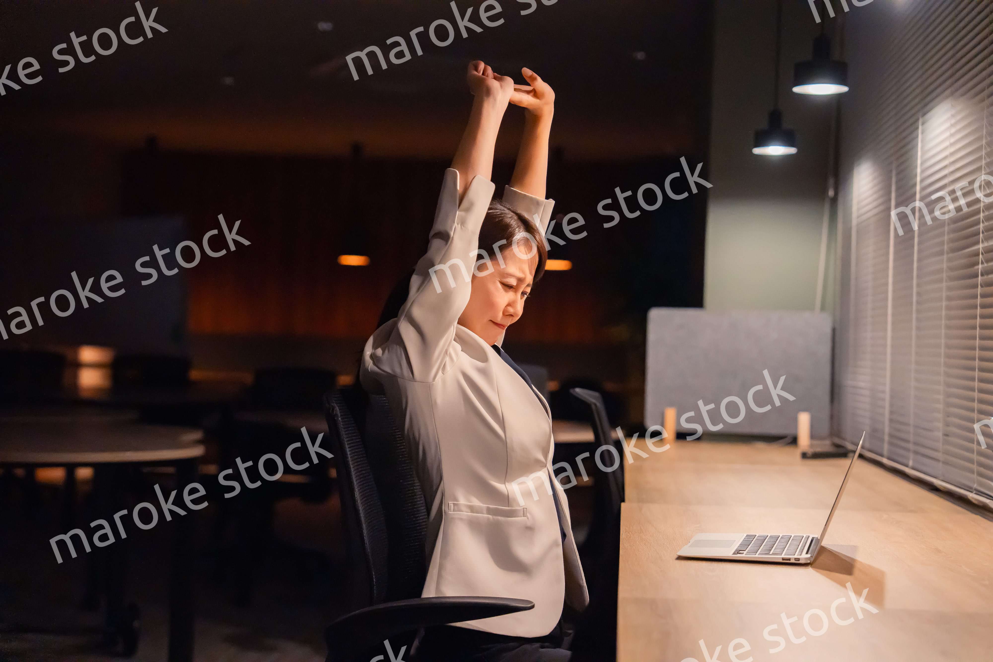 オフィスで暗くなるまで残業をして疲れる女性管理職