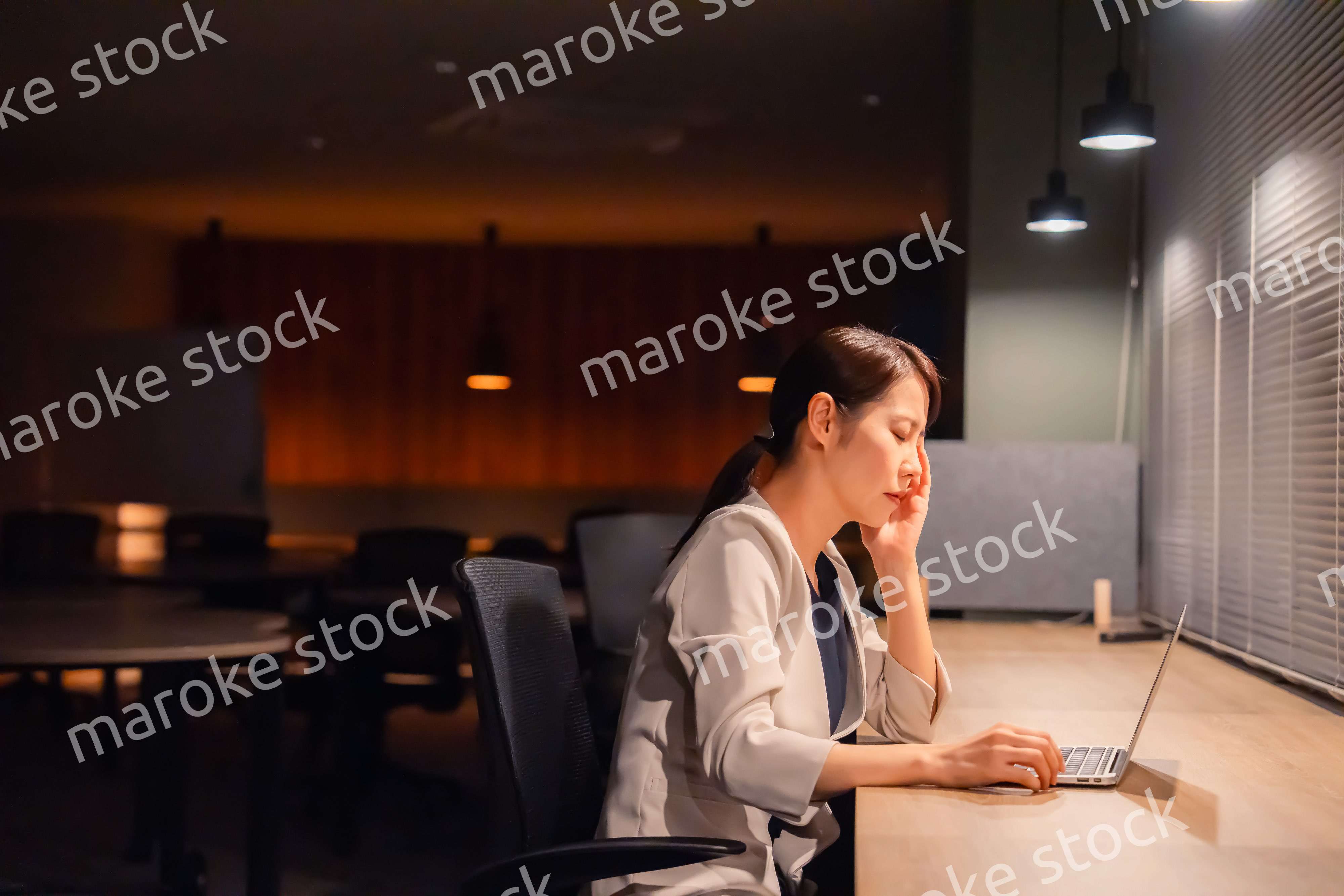 オフィスで暗くなるまで残業をして疲れる女性管理職