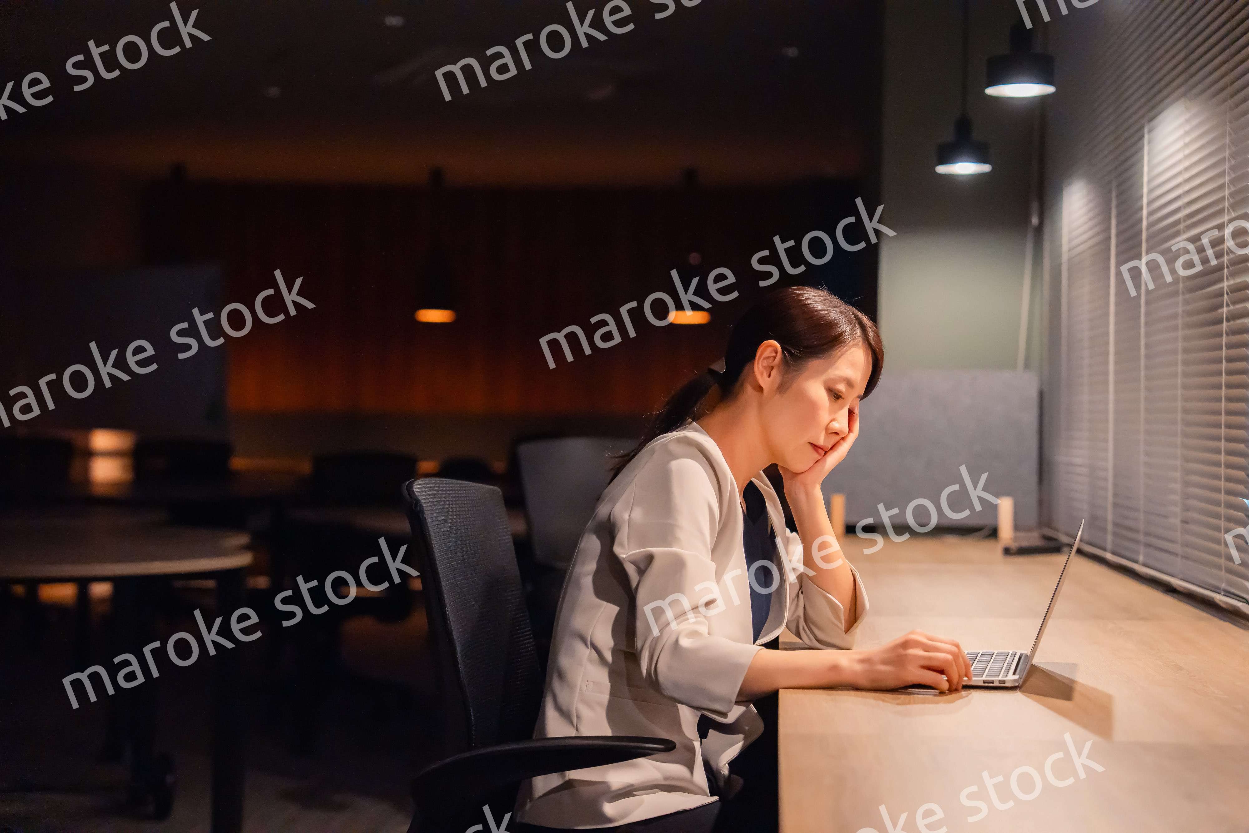 オフィスで暗くなるまで残業をして疲れる女性管理職