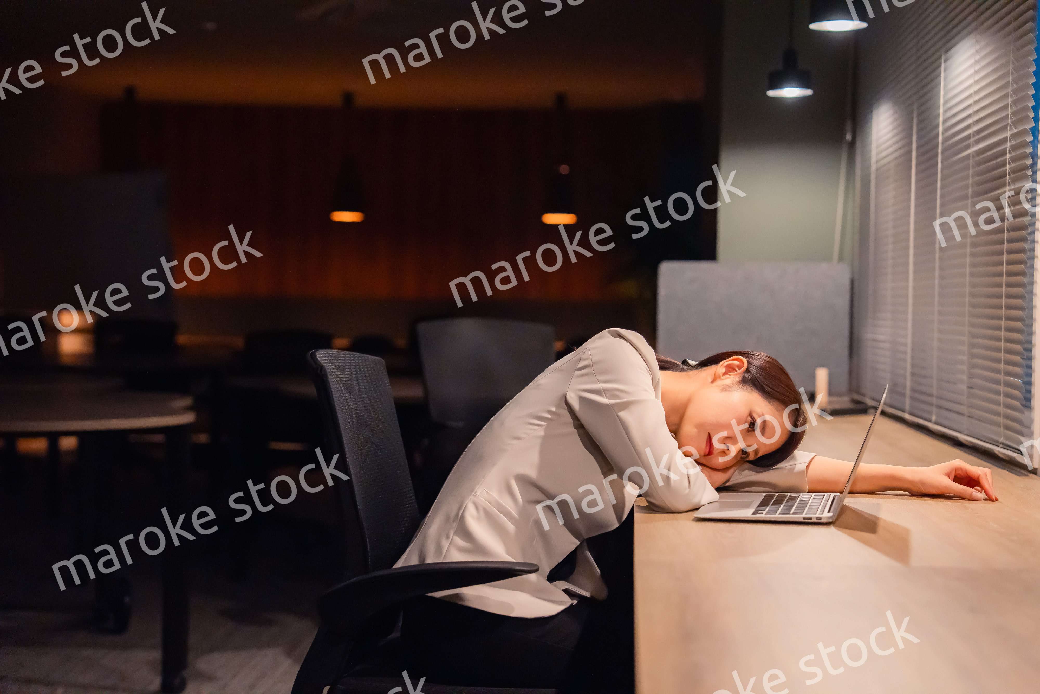 オフィスで暗くなるまで残業をして疲れる女性管理職