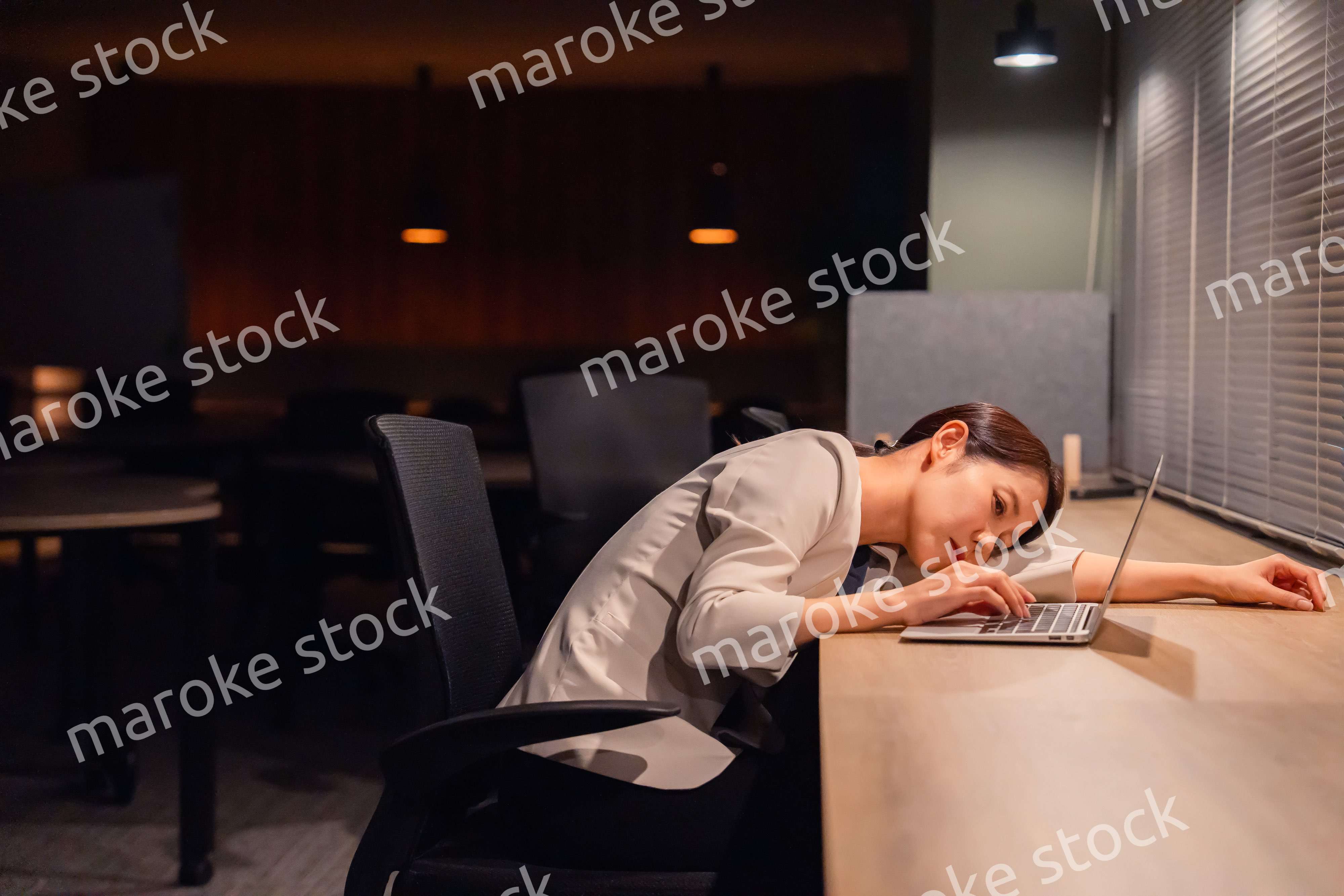 オフィスで暗くなるまで残業をして疲れる女性管理職