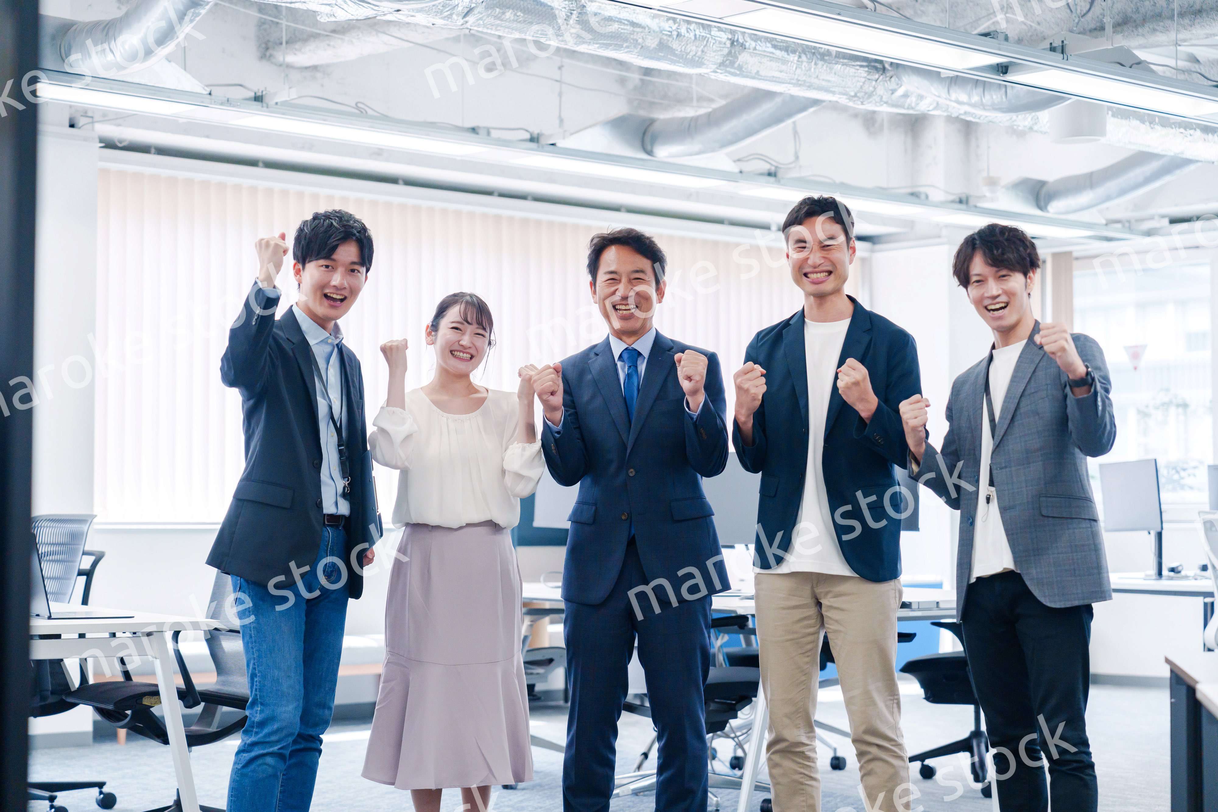 オフィスで笑顔でガッツポーズをするビジネスパーソン
