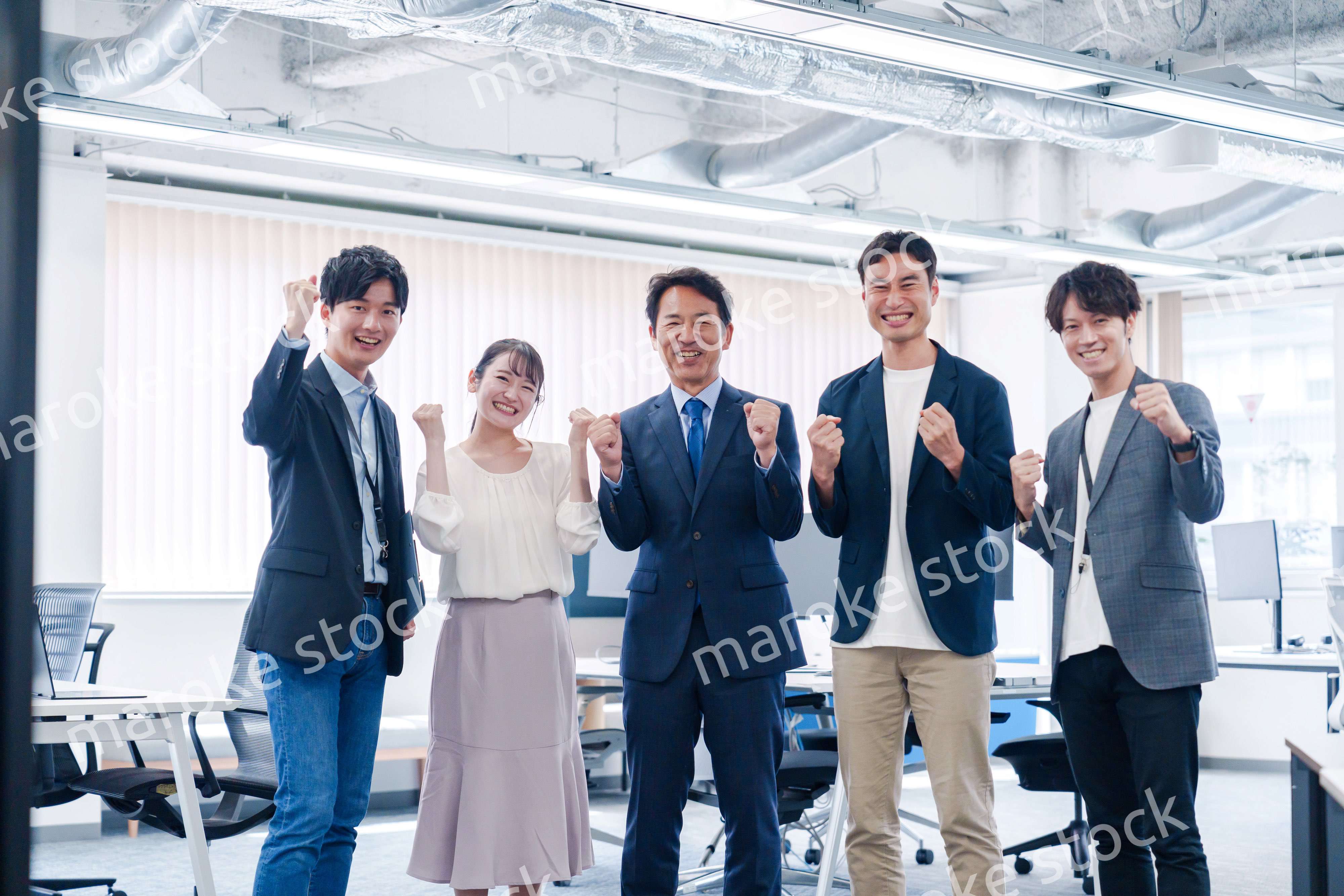 オフィスで笑顔でガッツポーズをするビジネスパーソン