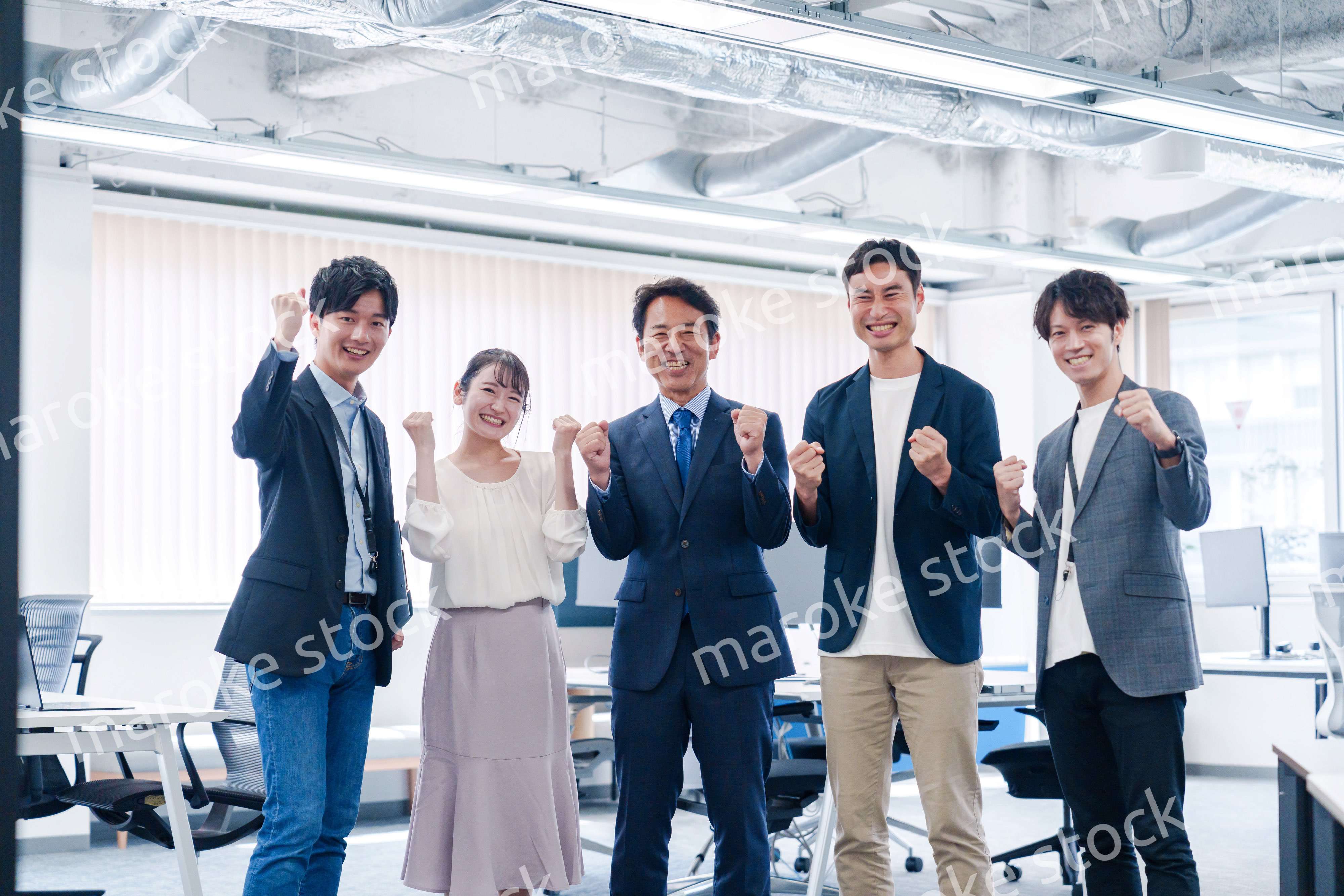 オフィスで笑顔でガッツポーズをするビジネスパーソン