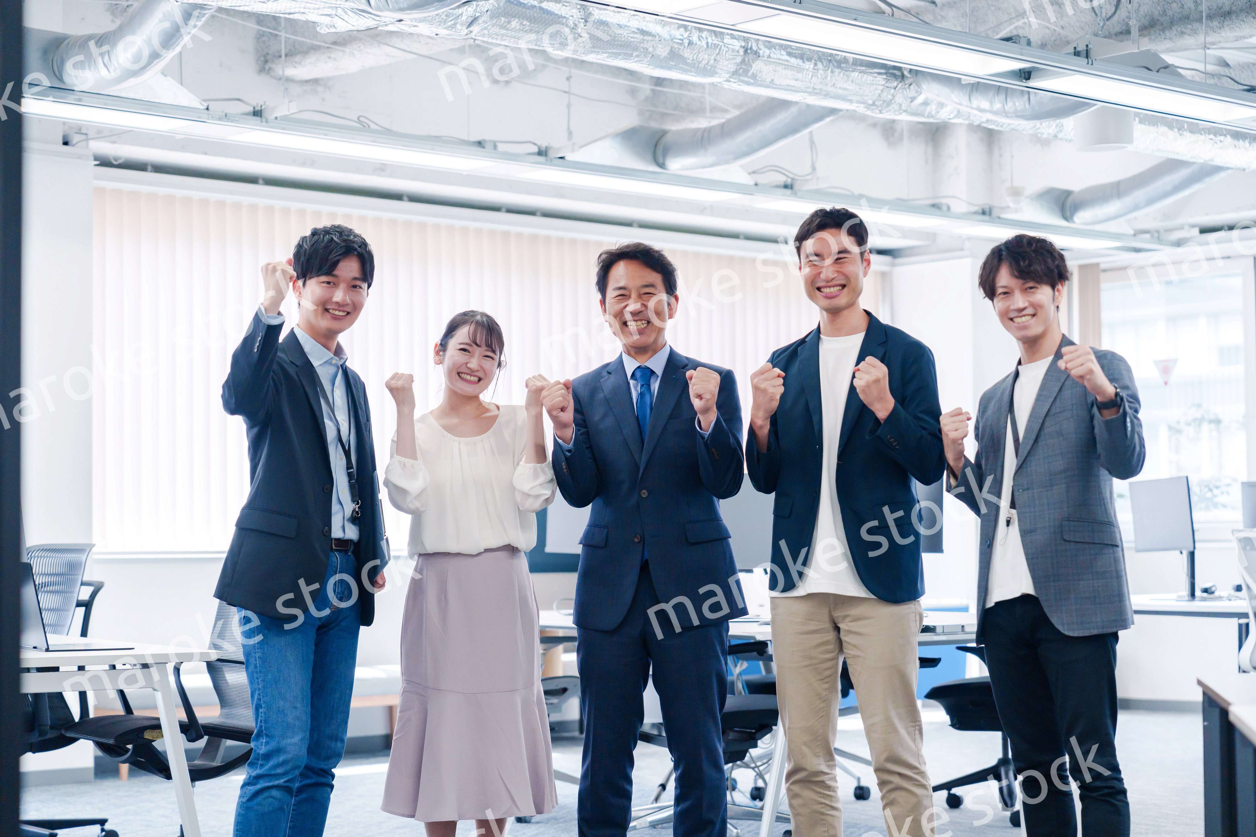 オフィスで笑顔でガッツポーズをするビジネスパーソン