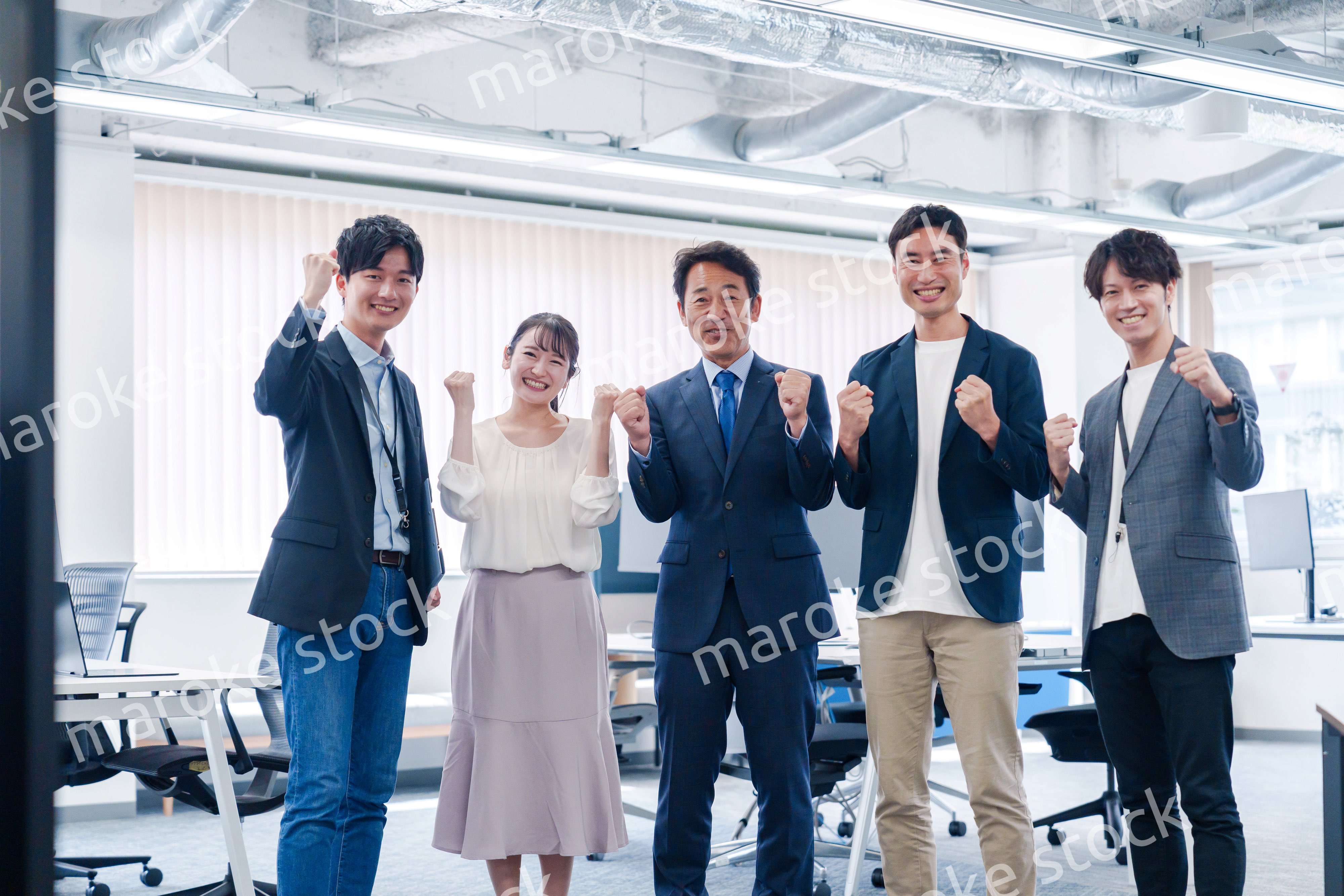オフィスで笑顔でガッツポーズをするビジネスパーソン