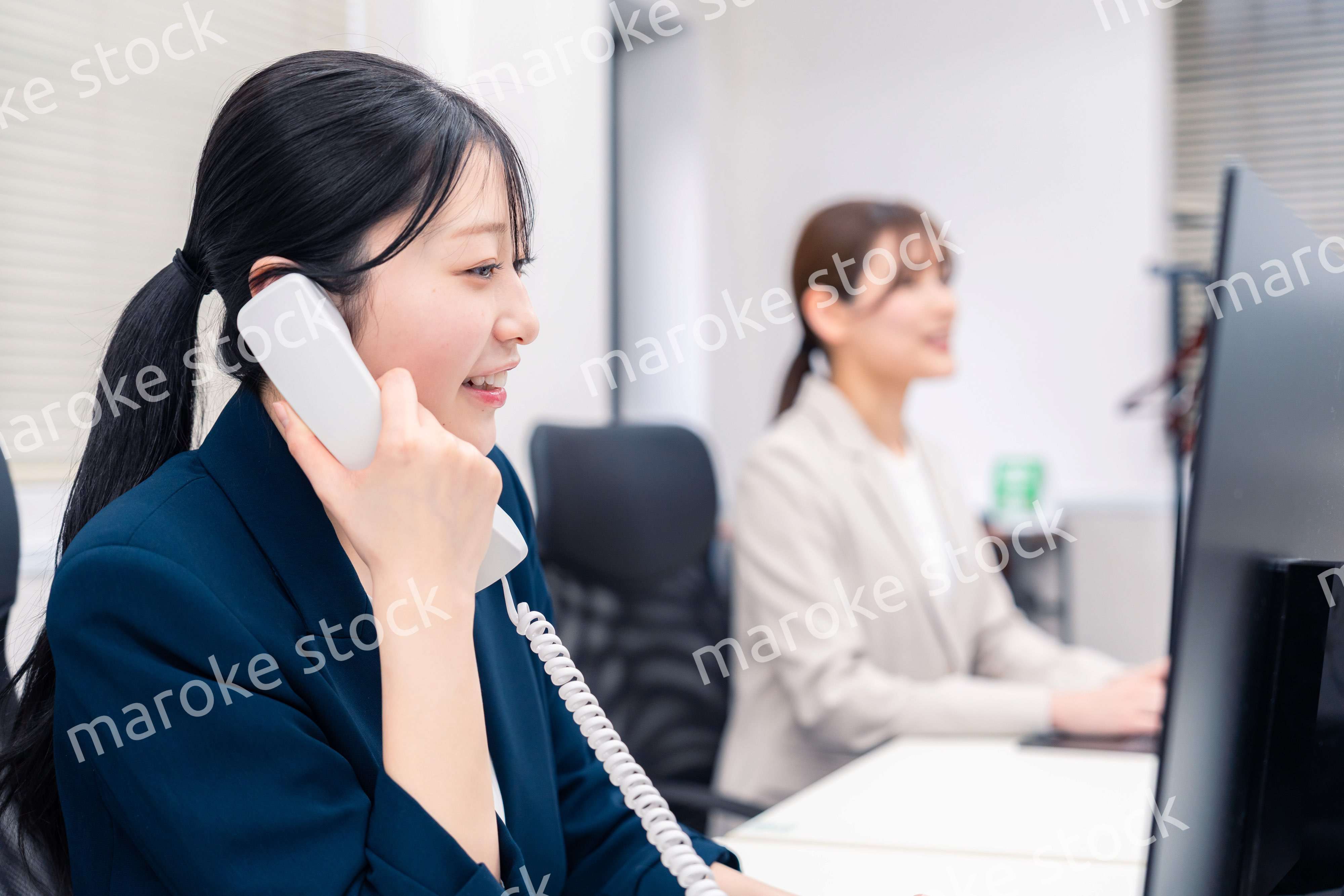 オフィスでにこやかに電話対応をするビジネスウーマン