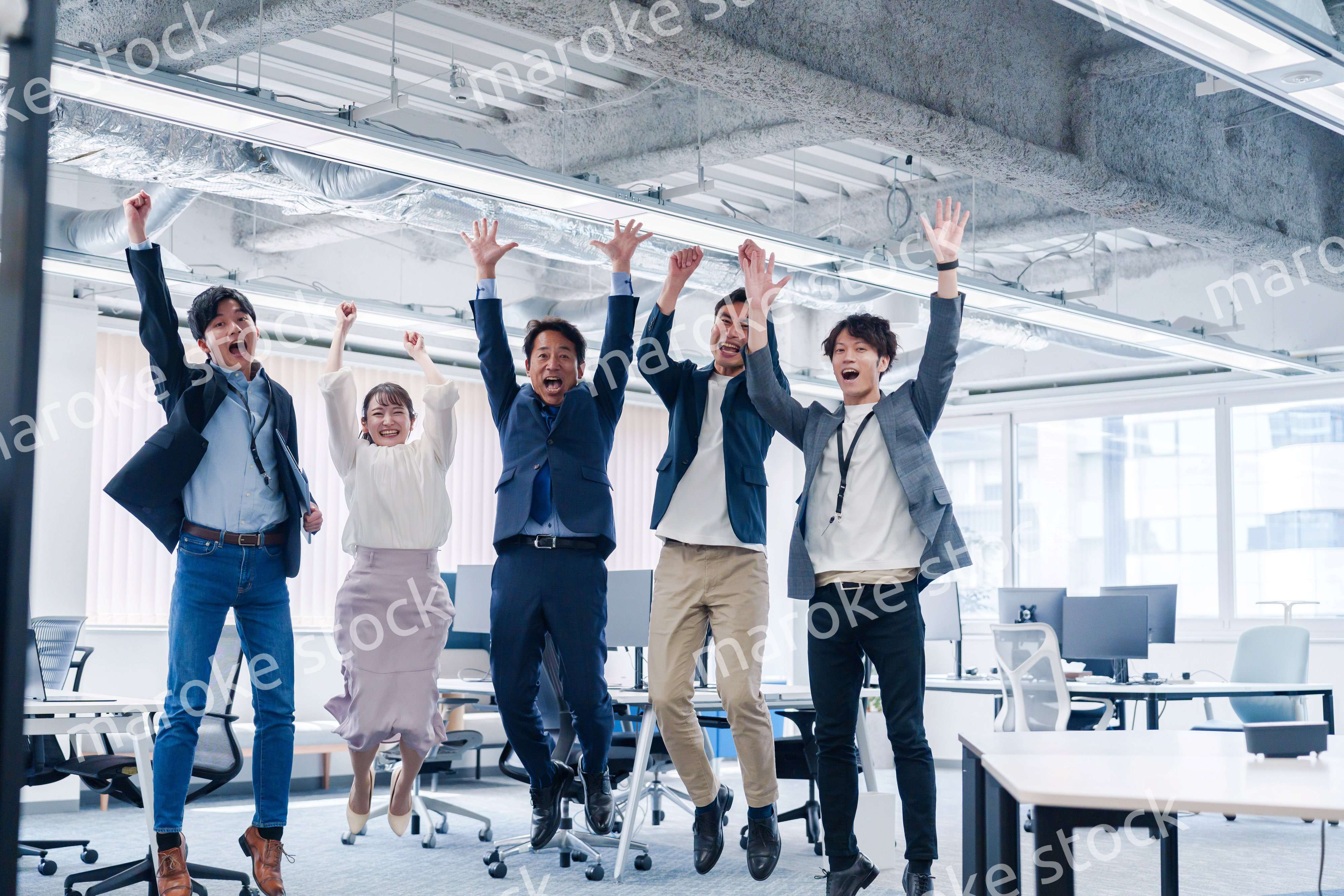 オフィスで大喜びをしてジャンプをするビジネスパーソン