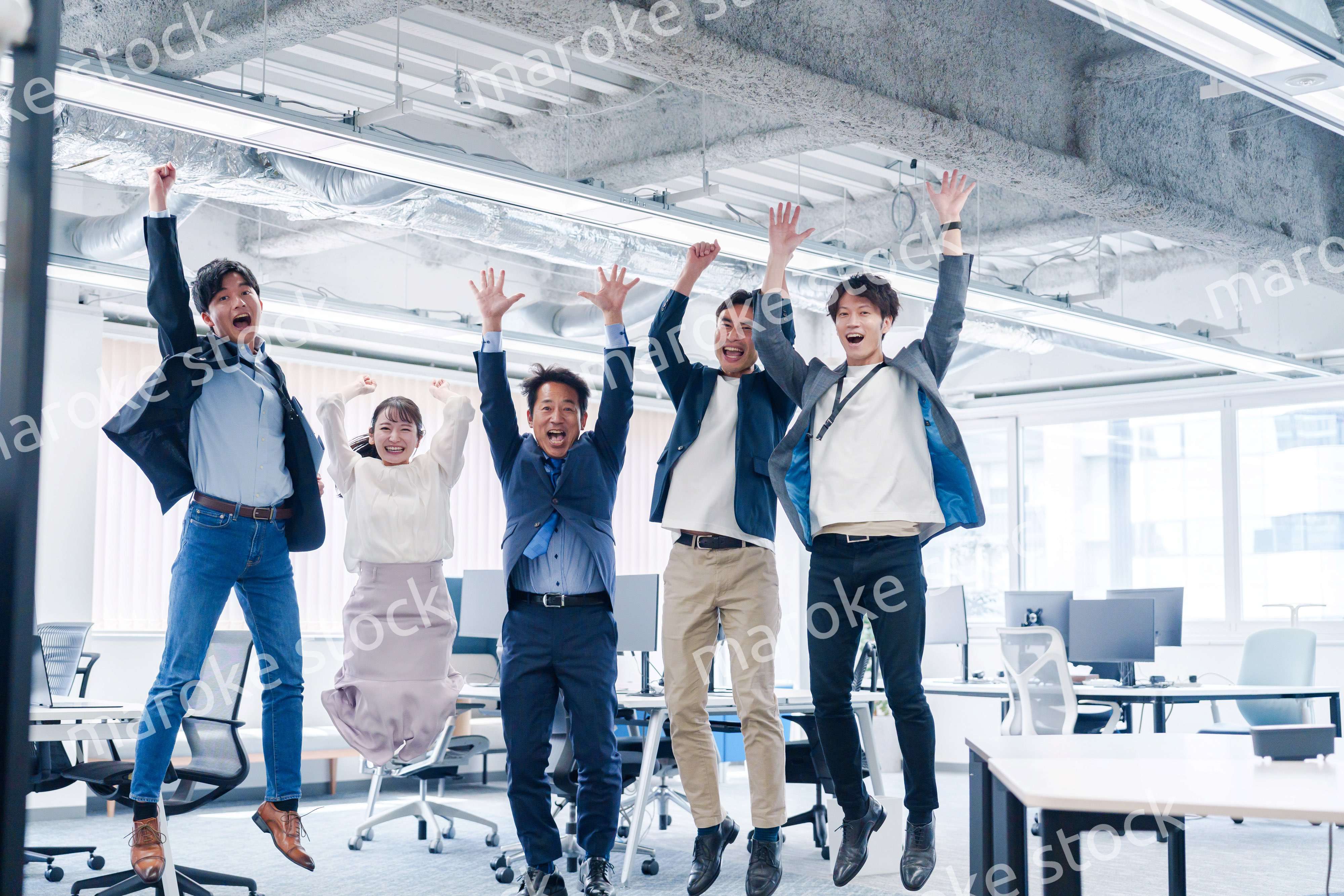 オフィスで大喜びをしてジャンプをするビジネスパーソン