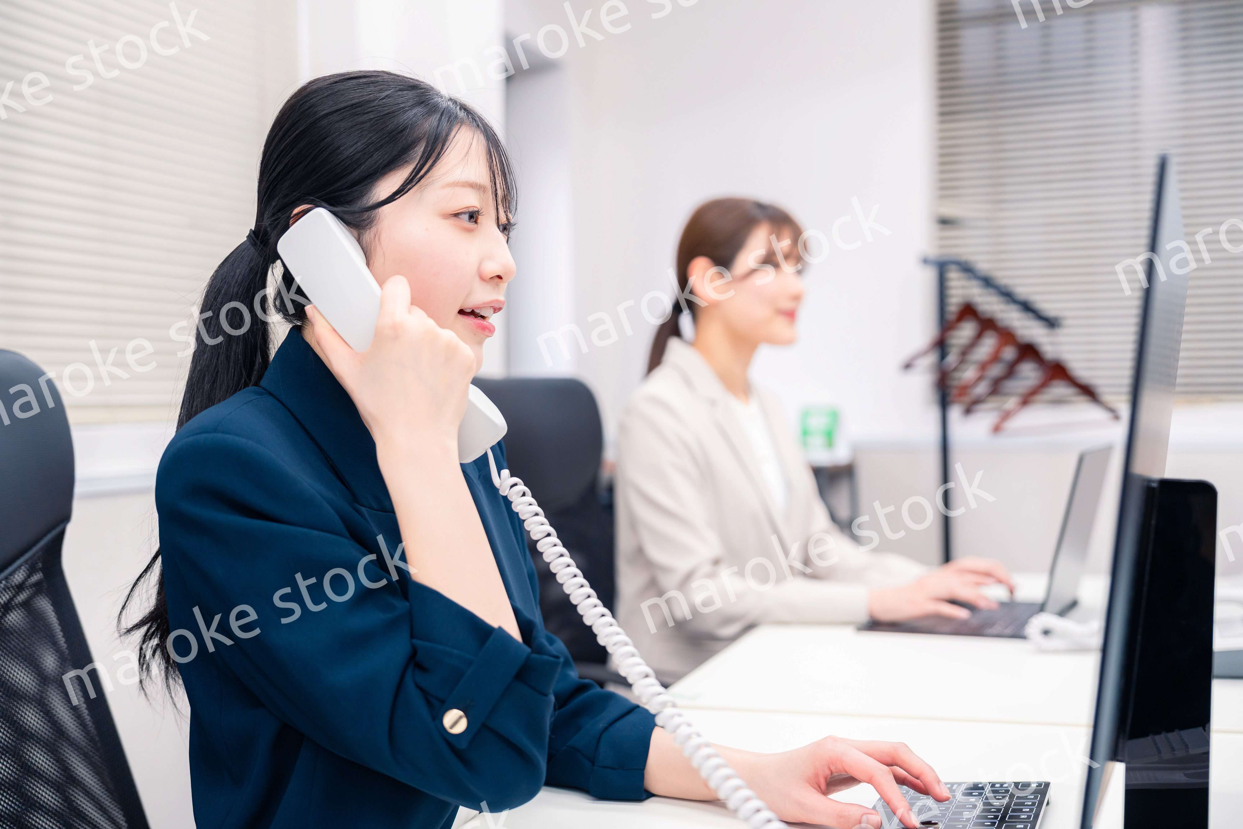 オフィスでにこやかに電話対応をするビジネスウーマン