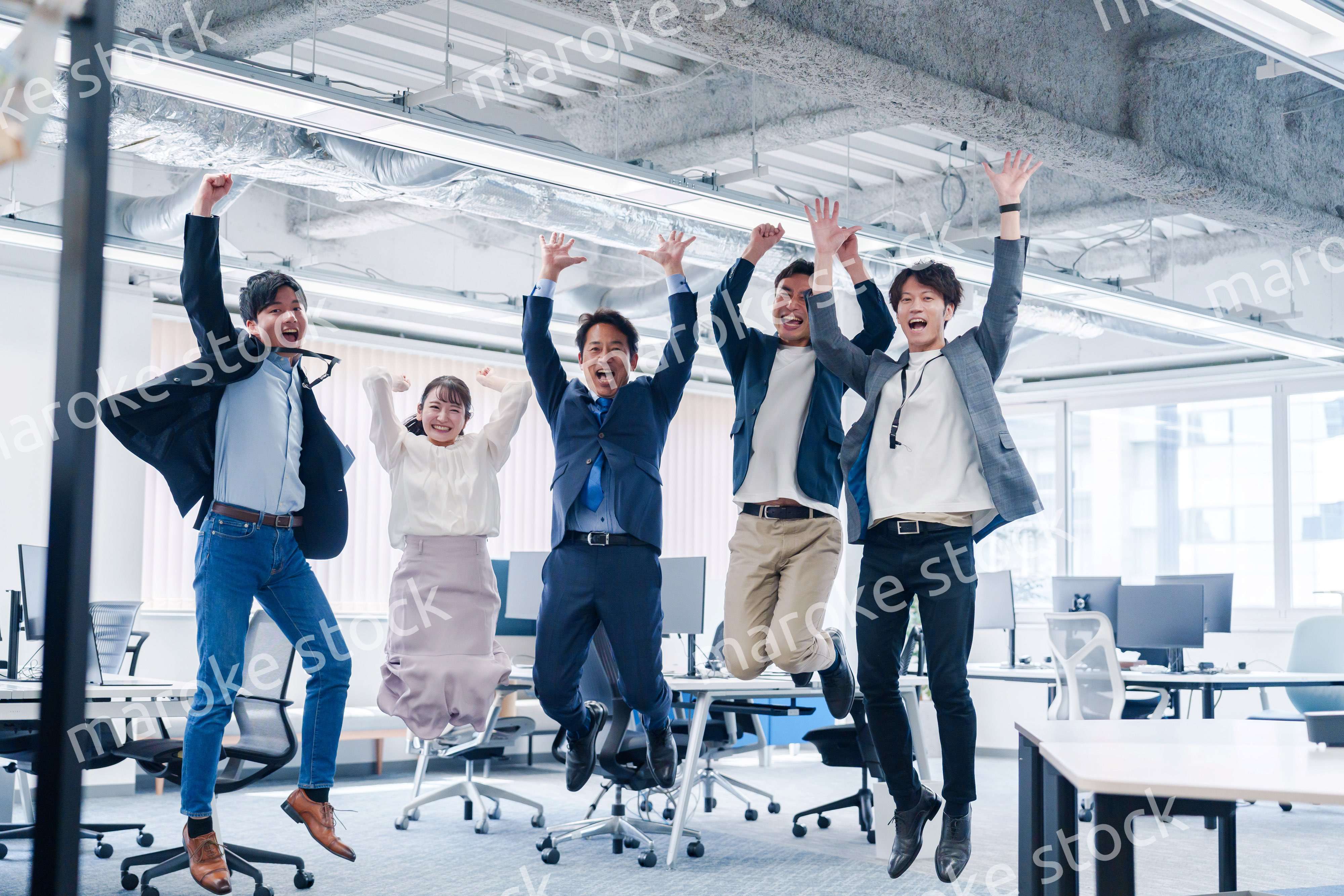 オフィスで大喜びをしてジャンプをするビジネスパーソン