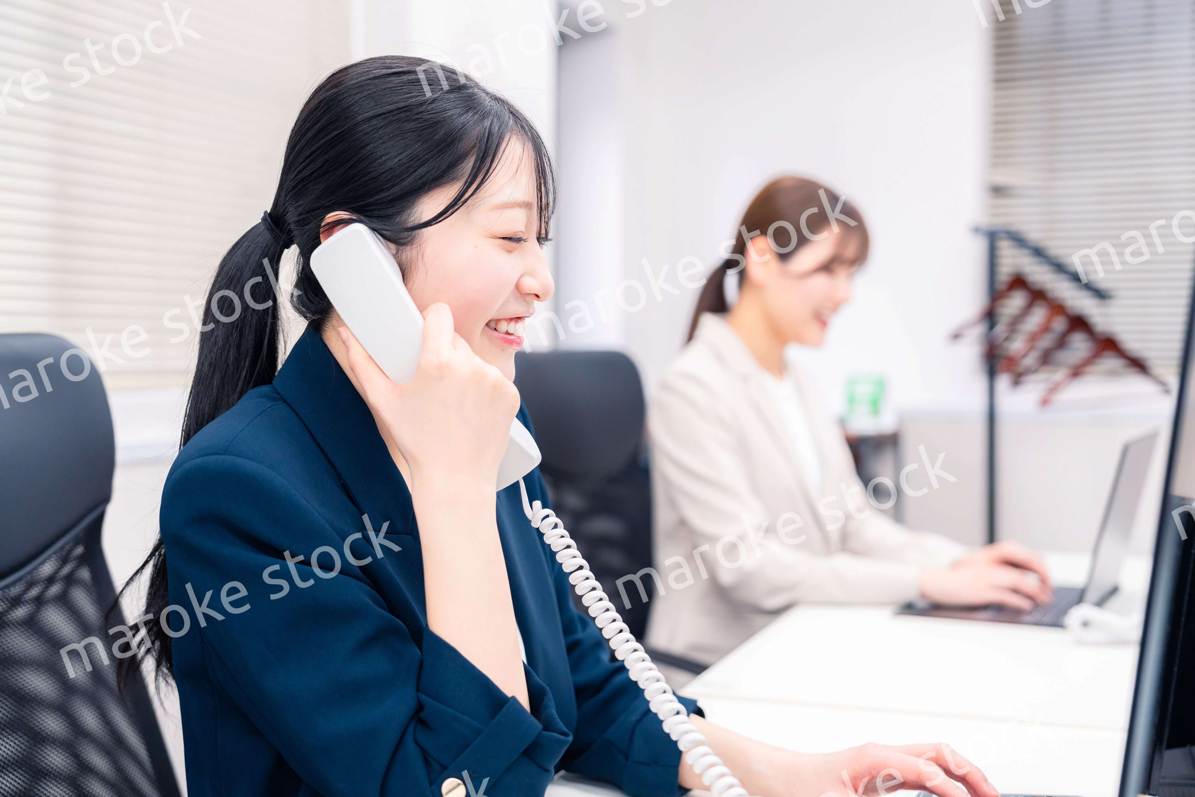 オフィスでにこやかに電話対応をするビジネスウーマン