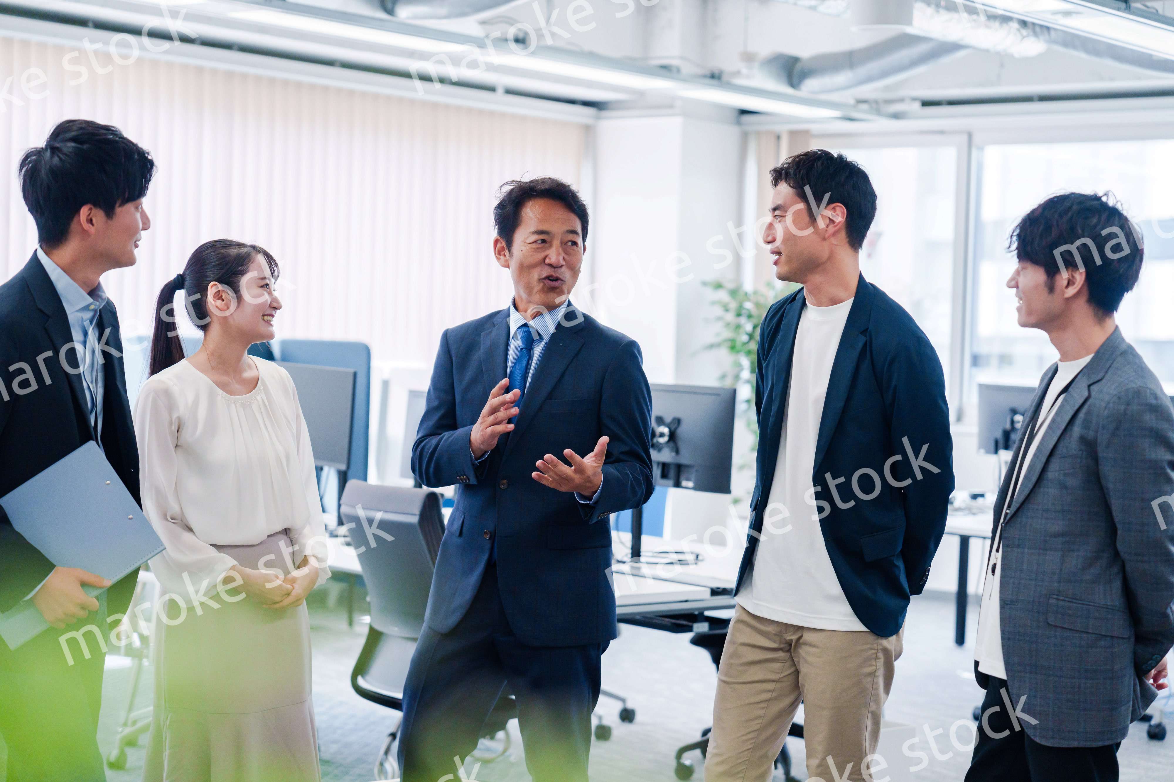 オフィスで立ち話をするビジネスパーソン