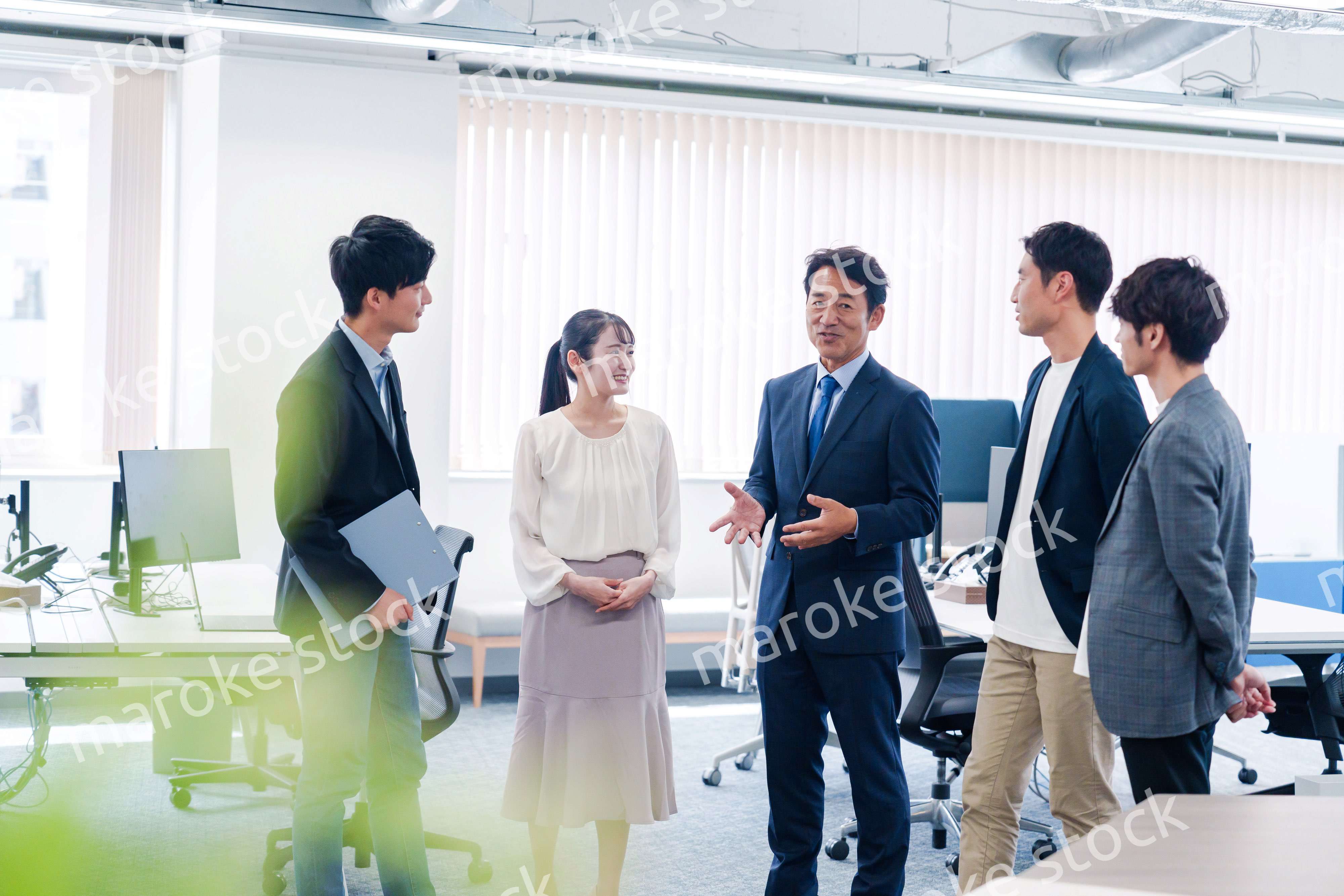 オフィスで立ち話をするビジネスパーソン