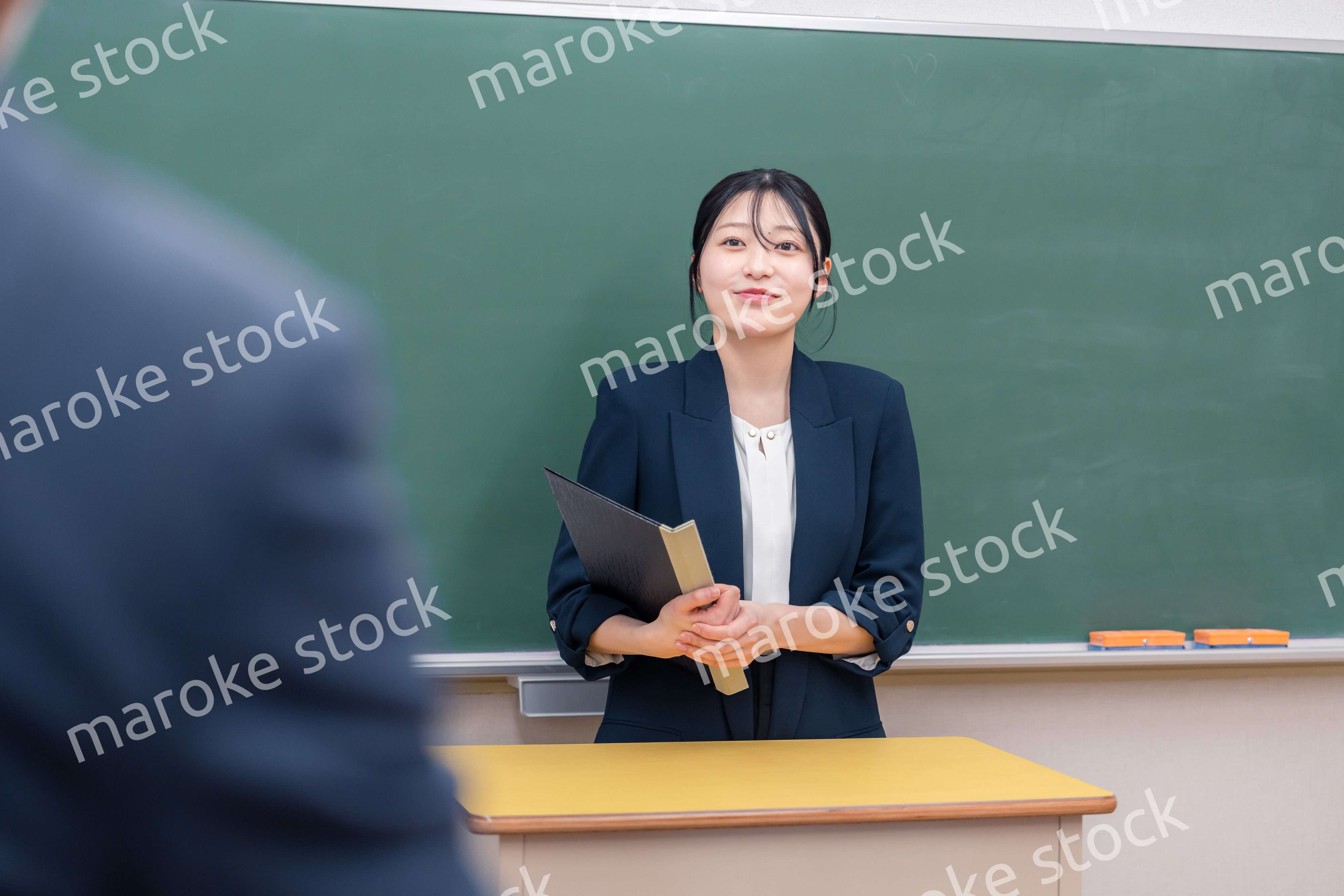 学校で教壇に立って授業をする若い女性教師