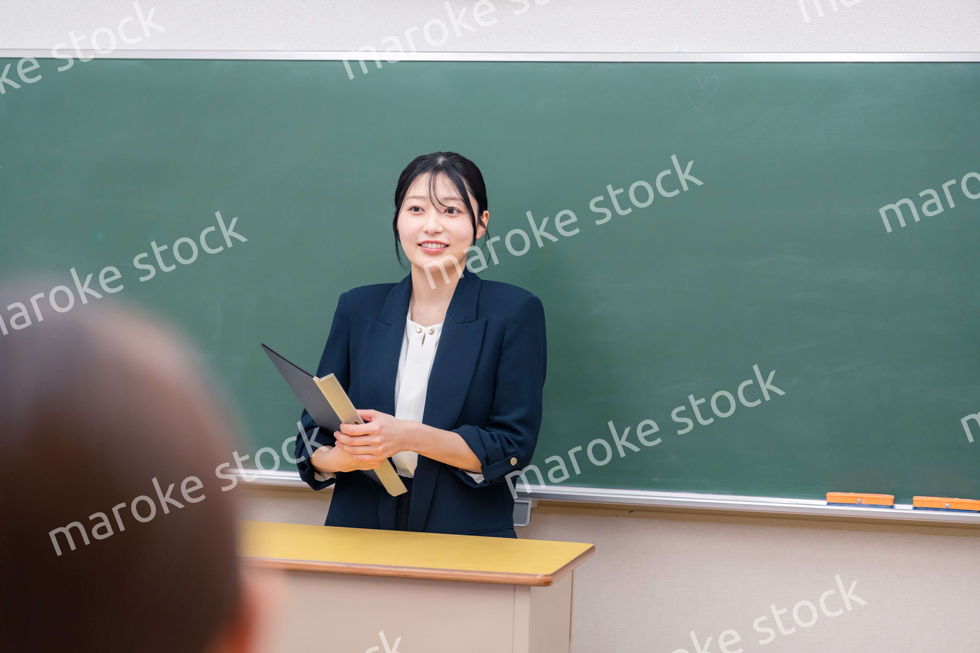 学校で教壇に立って授業をする若い女性教師