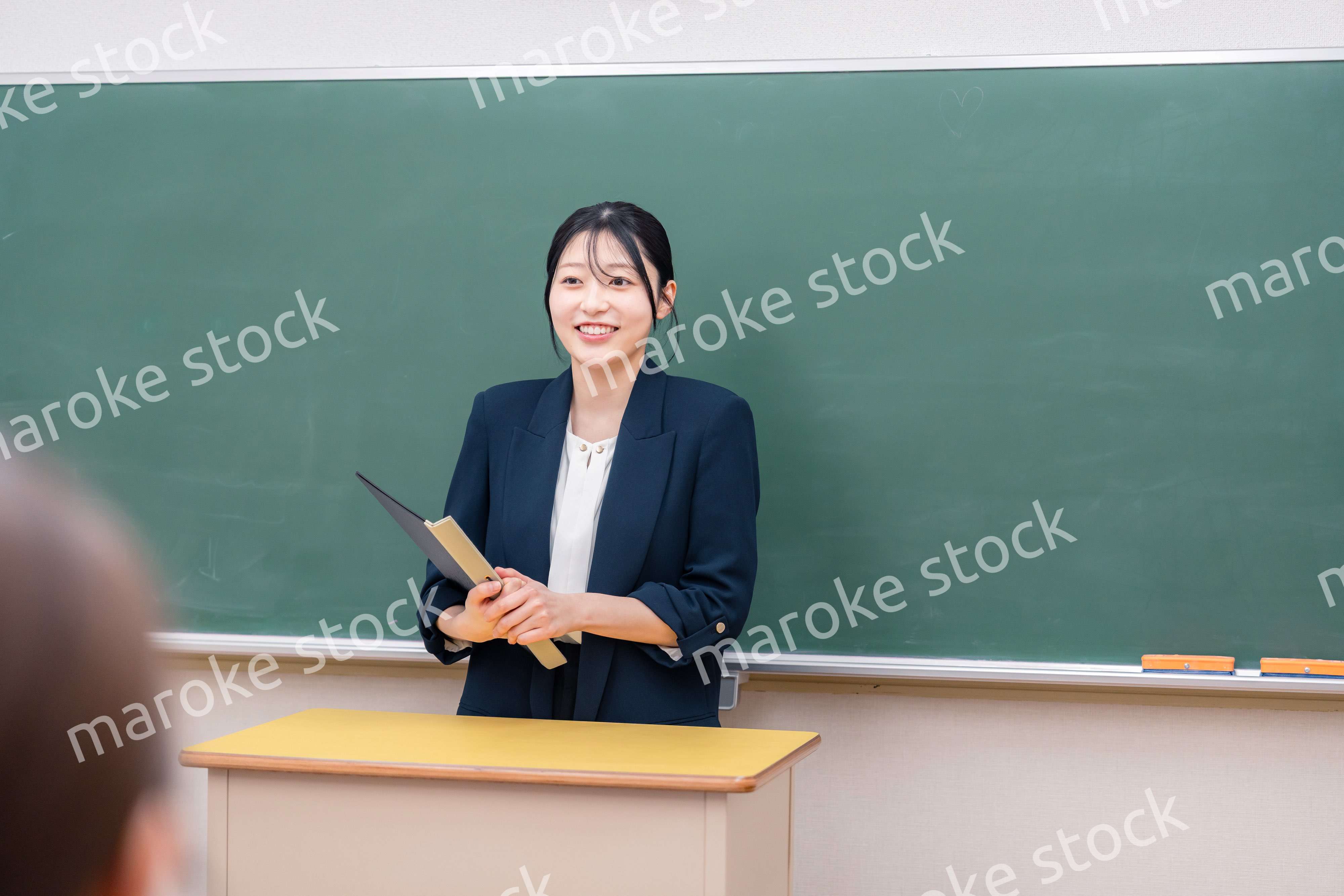 学校で教壇に立って授業をする若い女性教師