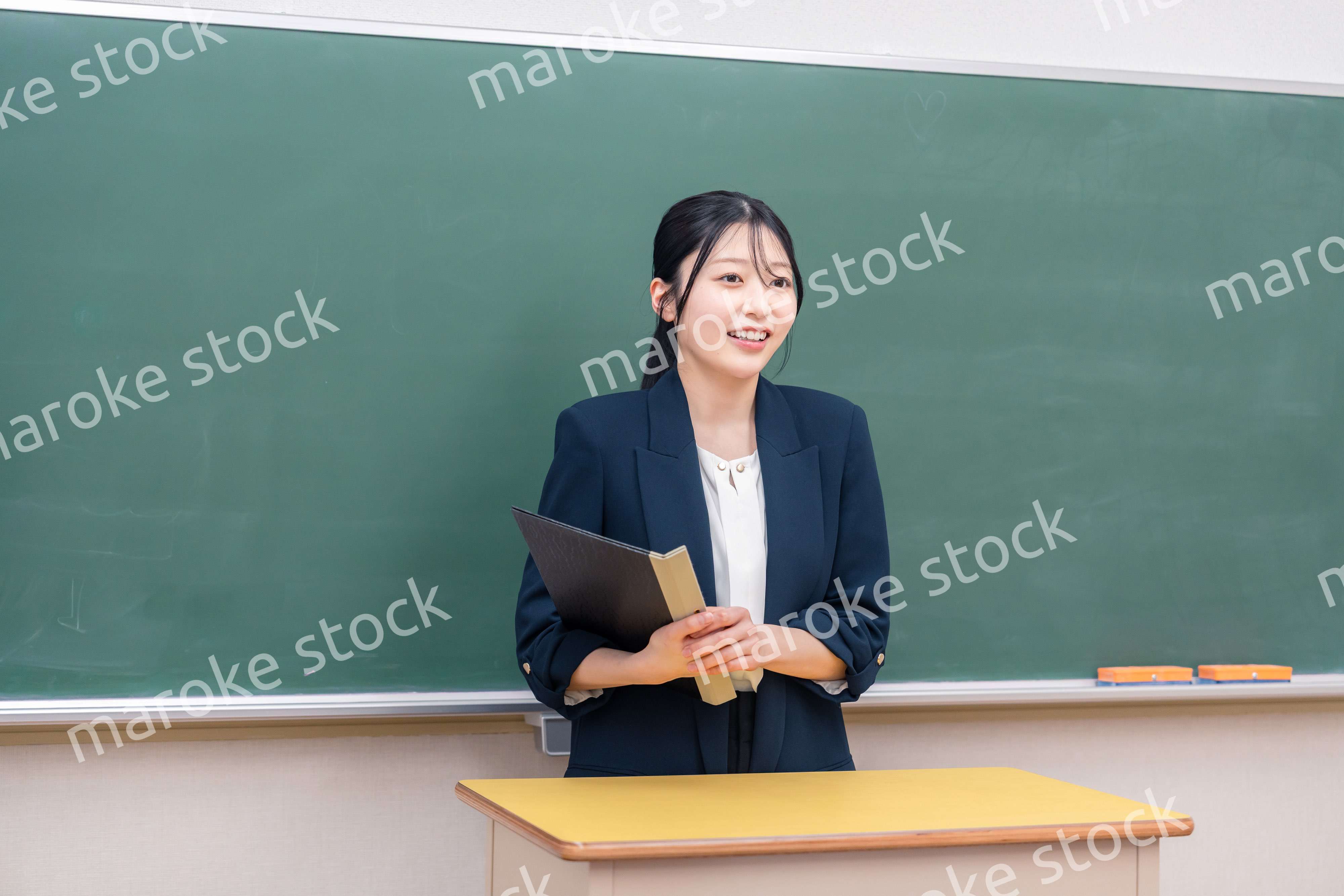 学校で教壇に立って授業をする若い女性教師