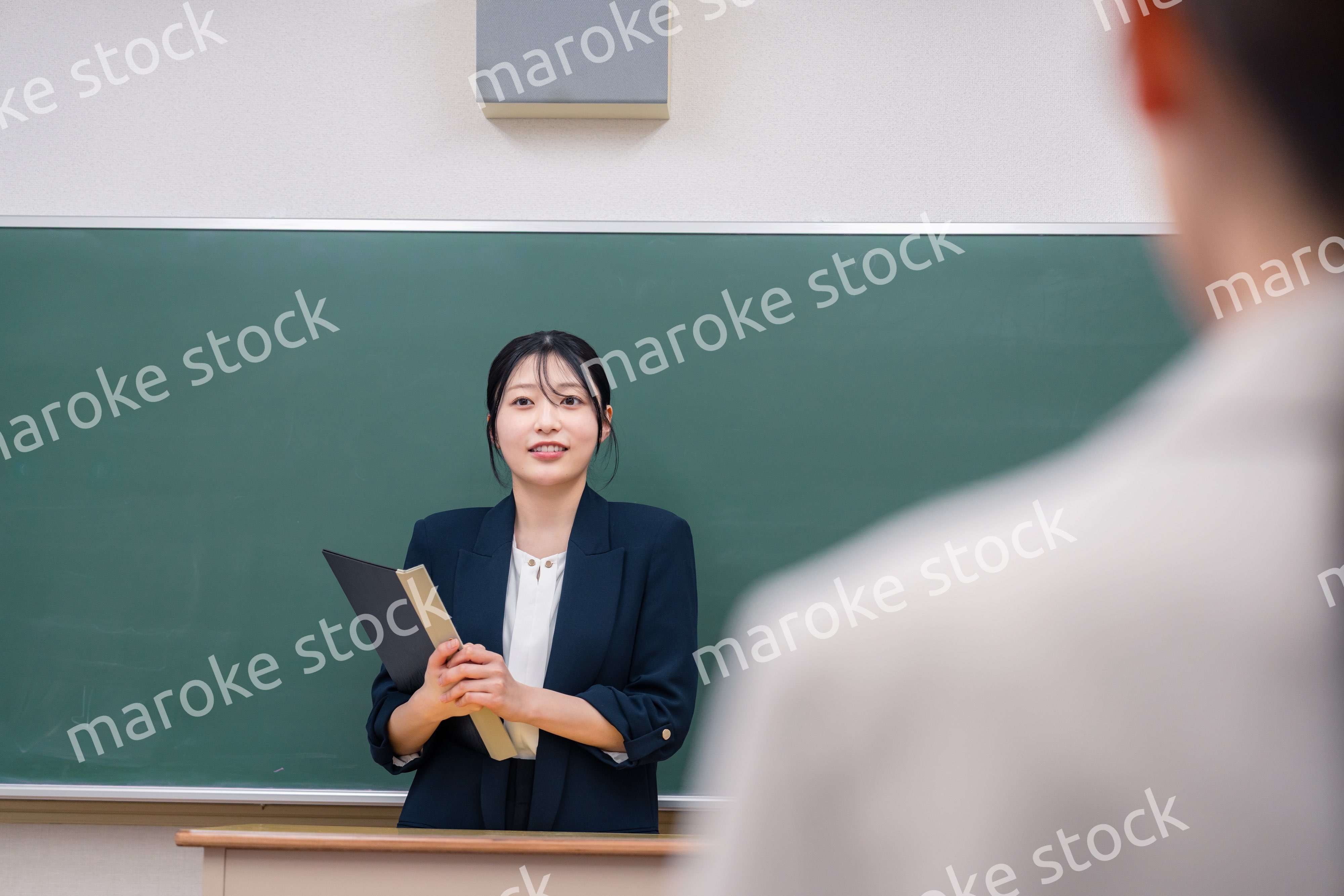 学校で教壇に立って授業をする若い女性教師