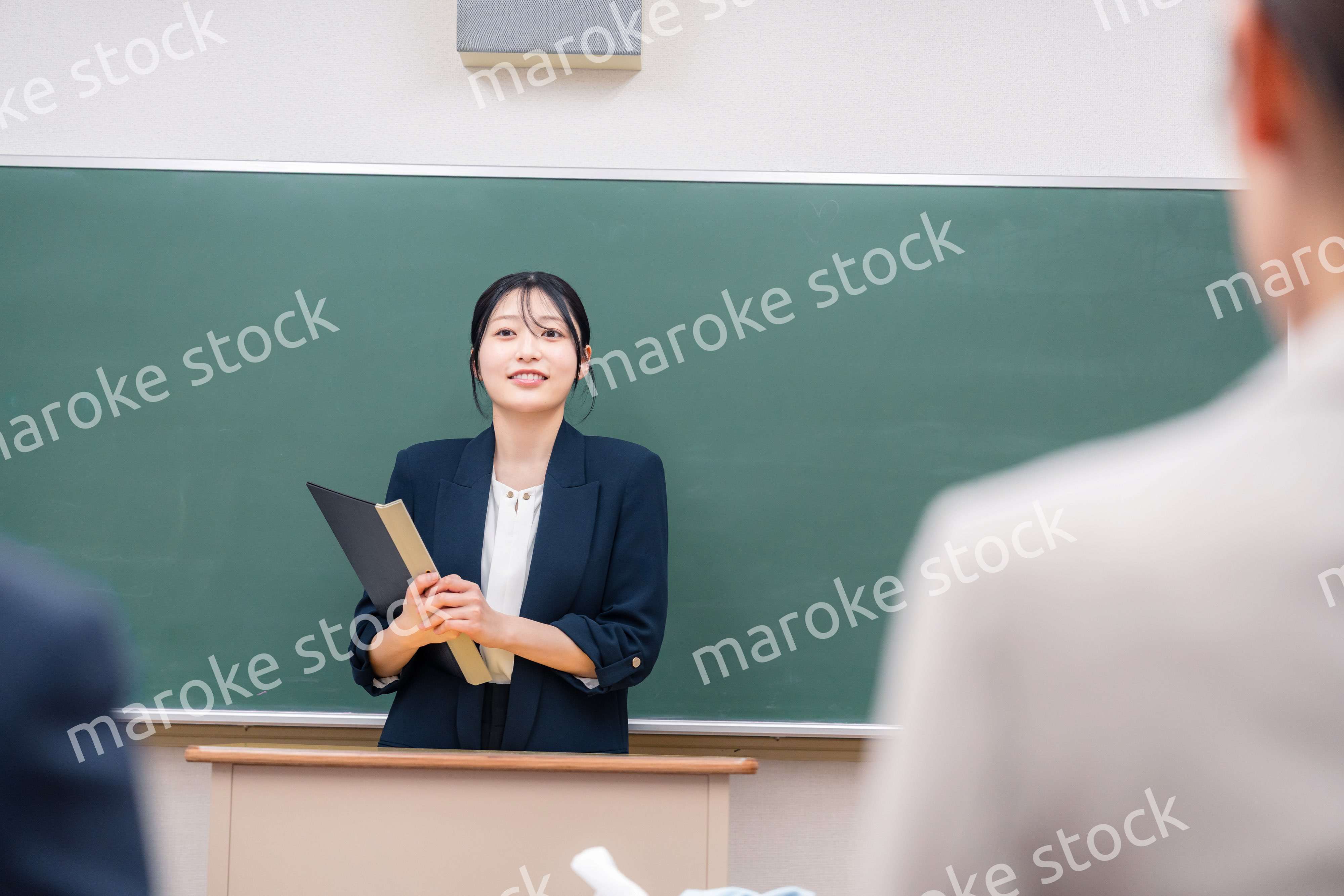 学校で教壇に立って授業をする若い女性教師