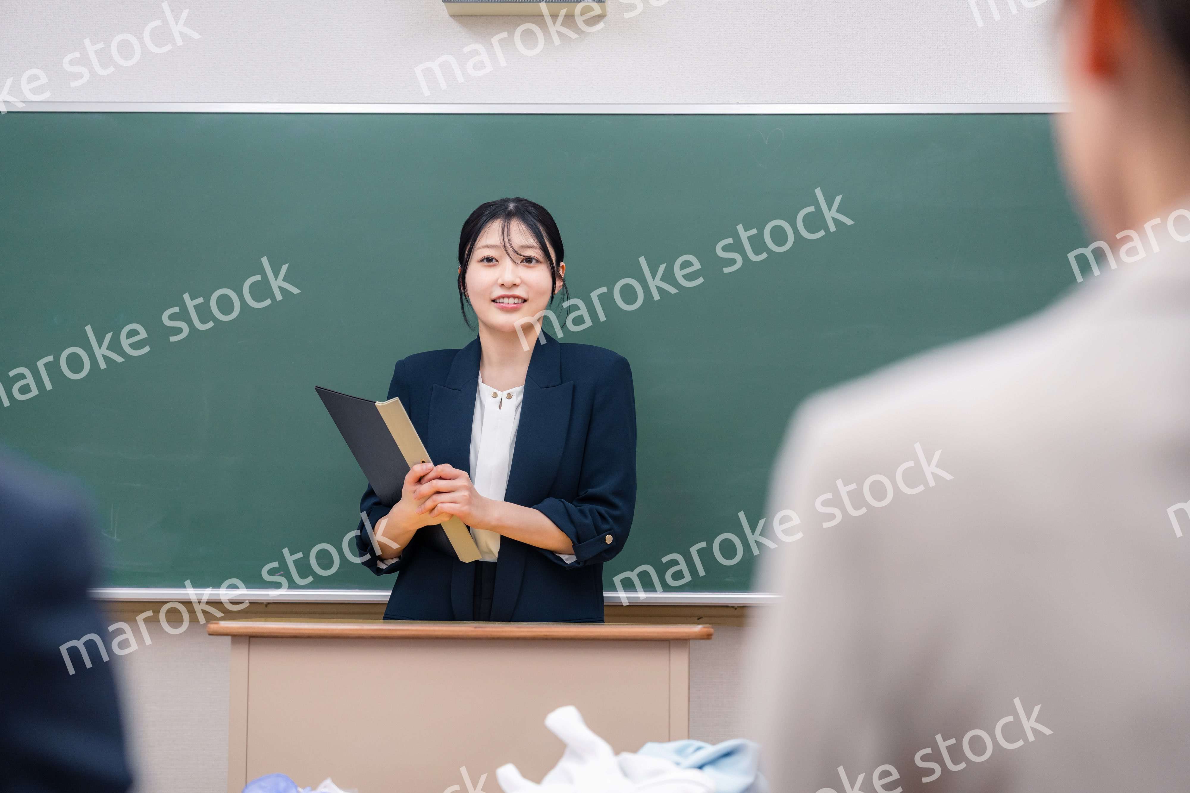 学校で教壇に立って授業をする若い女性教師