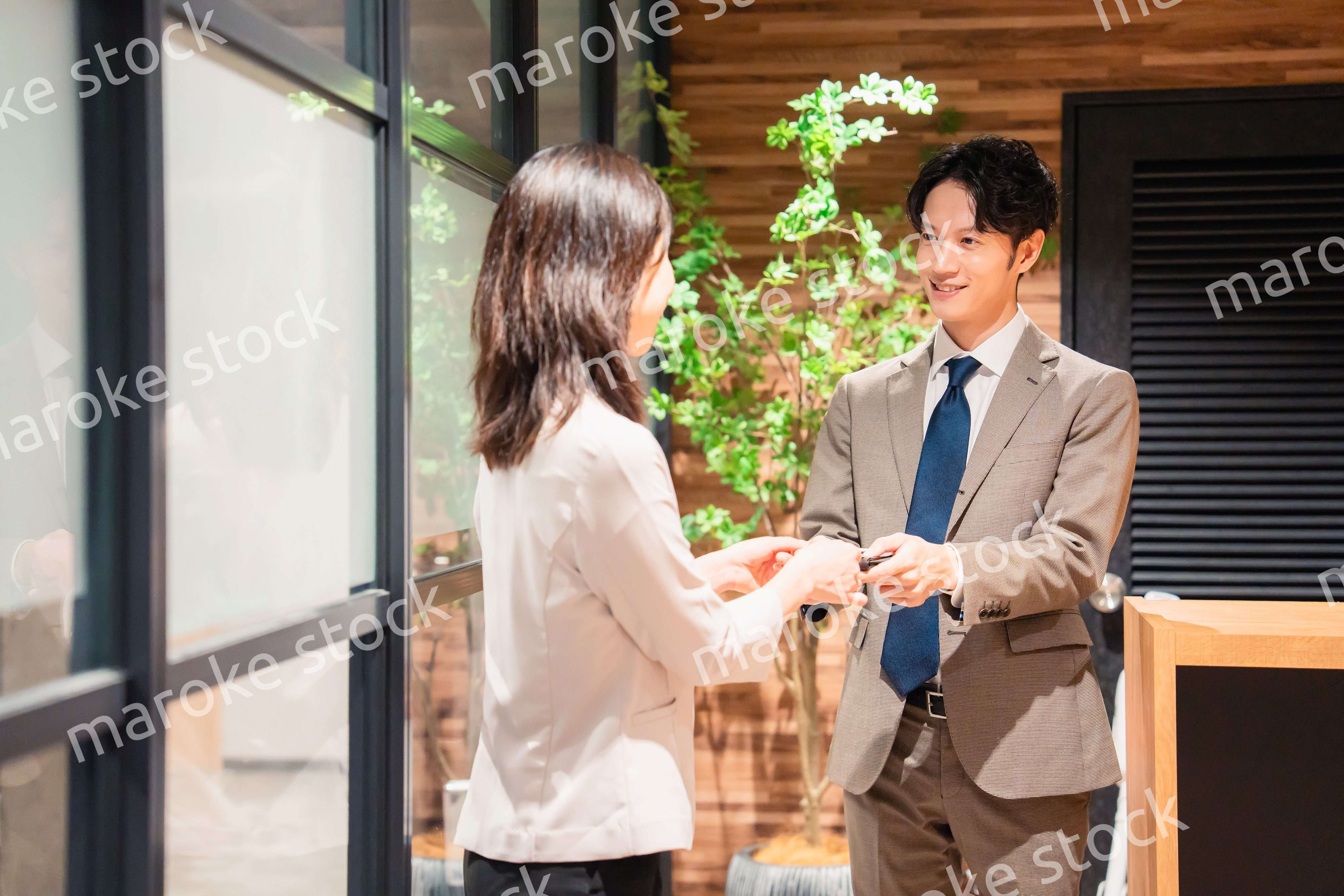 オフィスのエントランスで名刺交換をするビジネスパーソン